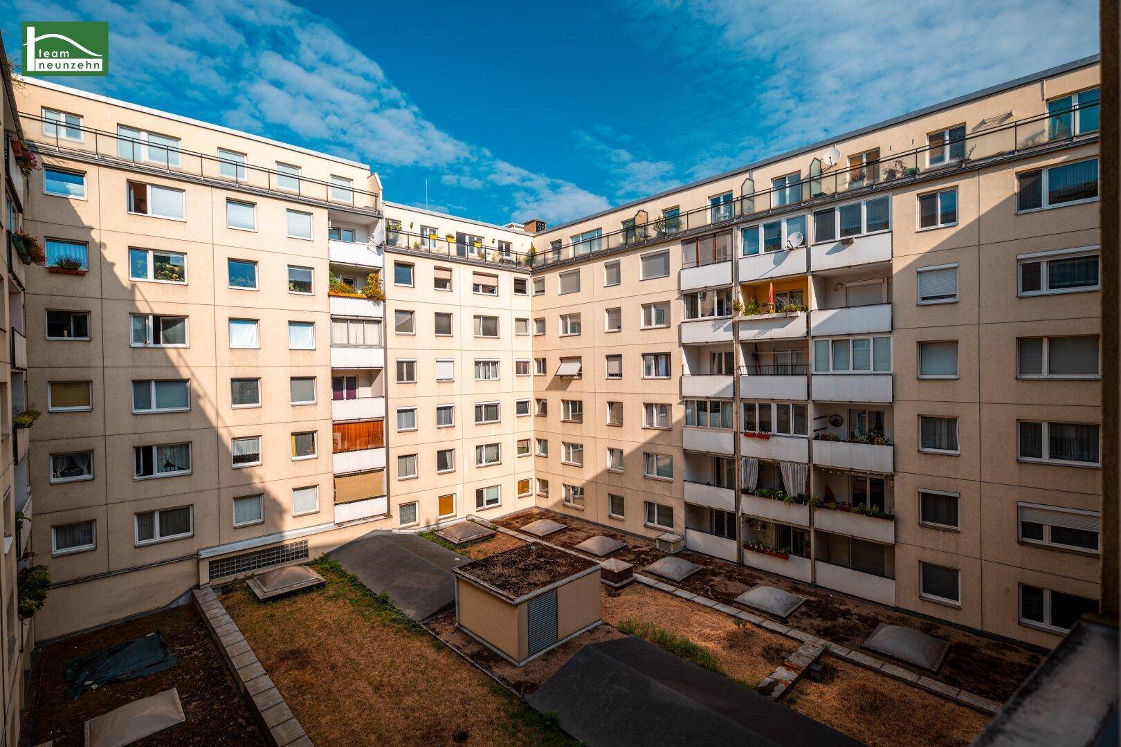 Innenhof eines Wohnkomplexes mit begrünten Dächern und zahlreichen Fenstern.