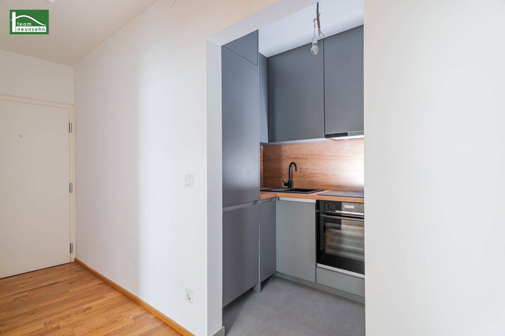 Kompakte Küchenzeile mit integriertem Kühlschrank und modernen grauen Fronten.