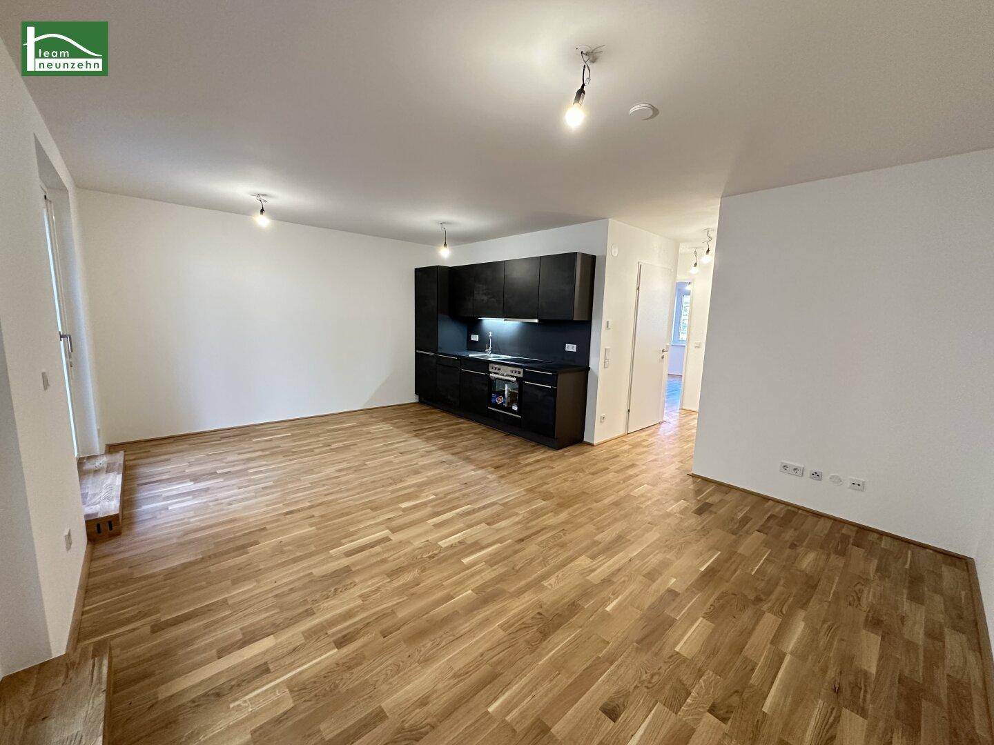 Geräumiger offener Wohnbereich mit Holzboden und einer modernen Küchenzeile.