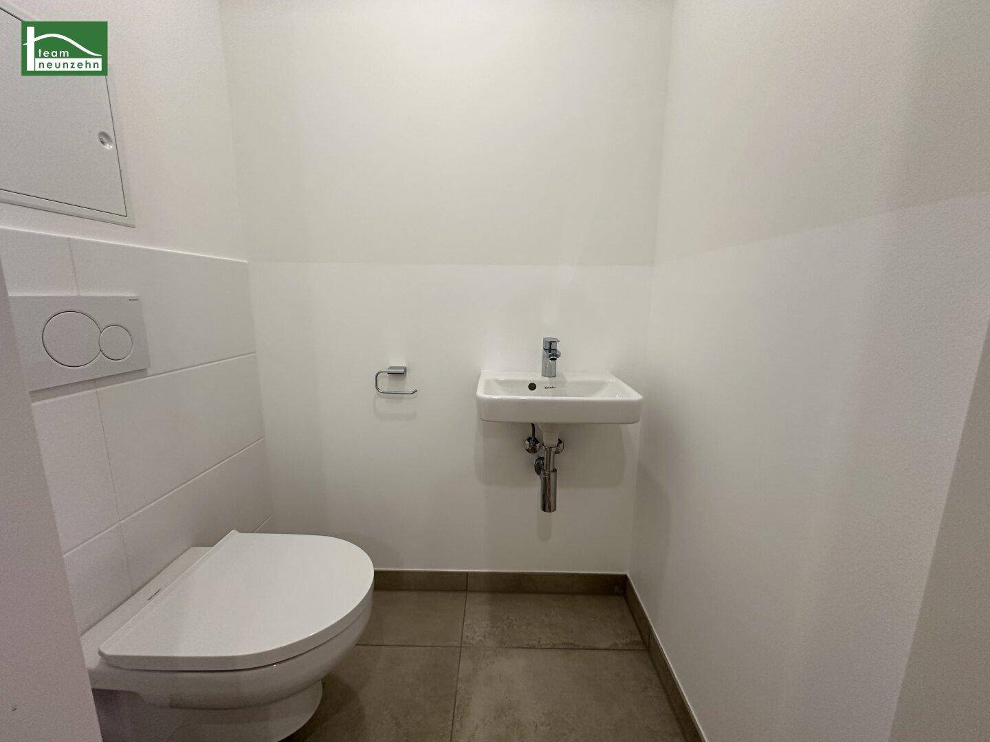 Modernes Gäste-WC mit wandhängender Toilette und kleinem Waschbecken.