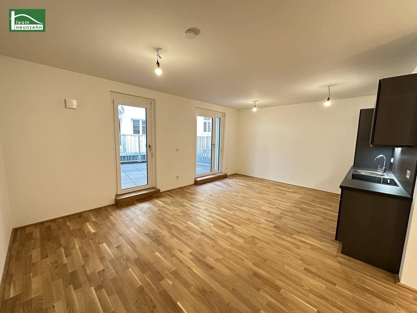Offener Wohnbereich mit Holzboden und Zugang zu zwei Balkonen oder Terrassen.