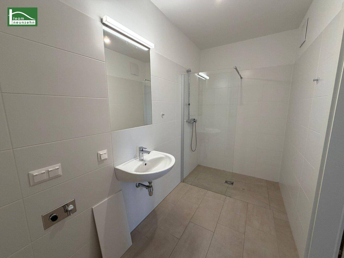 Modernes Badezimmer mit weißen Fliesen, Einzelwaschbecken und ebenerdiger Dusche.
