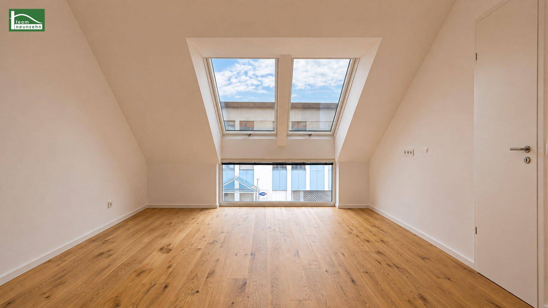Heller, leerer Dachgeschossraum mit Holzboden und großen Fenstern, ideal als Schlafzimmer.