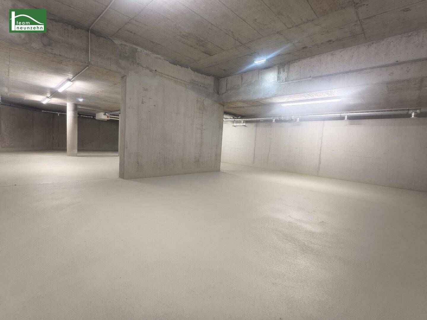 Geräumiger Beton-Kellerraum mit glattem Boden und sichtbaren Deckeninstallationen.