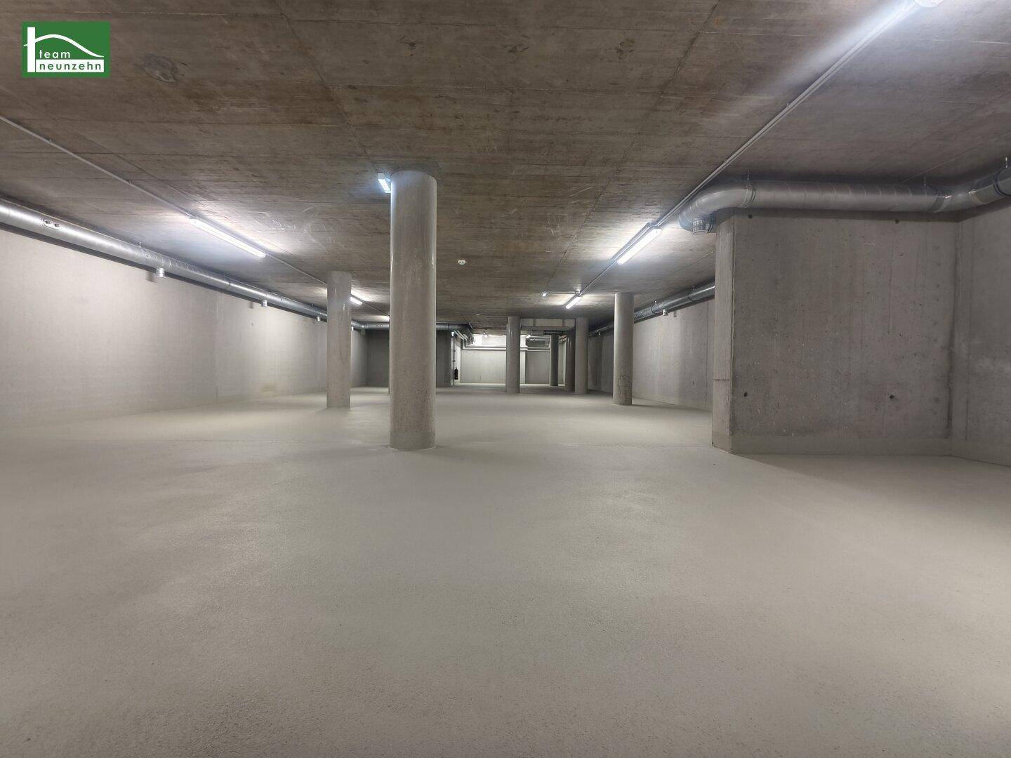 Weitläufiger Untergeschossraum mit Betonpfeilern, glattem Boden und funktionaler Deckenbeleuchtung.