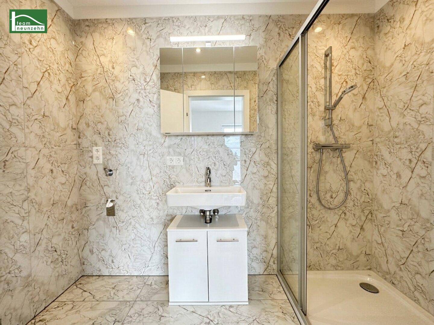 Modernes Badezimmer mit Marmoroptik-Fliesen, Einzelwaschbecken und begehbarer Dusche.