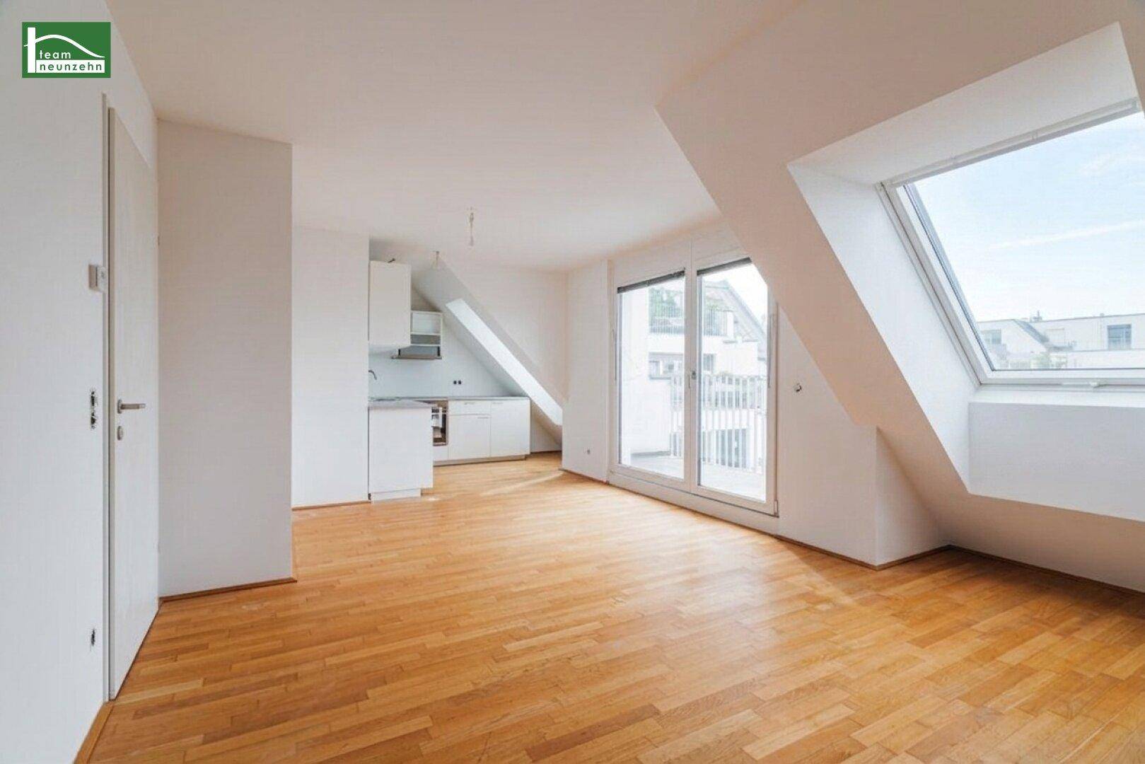 Heller Dachgeschossraum mit Holzboden, großen Dachfenstern und Zugang zu einem Balkon.