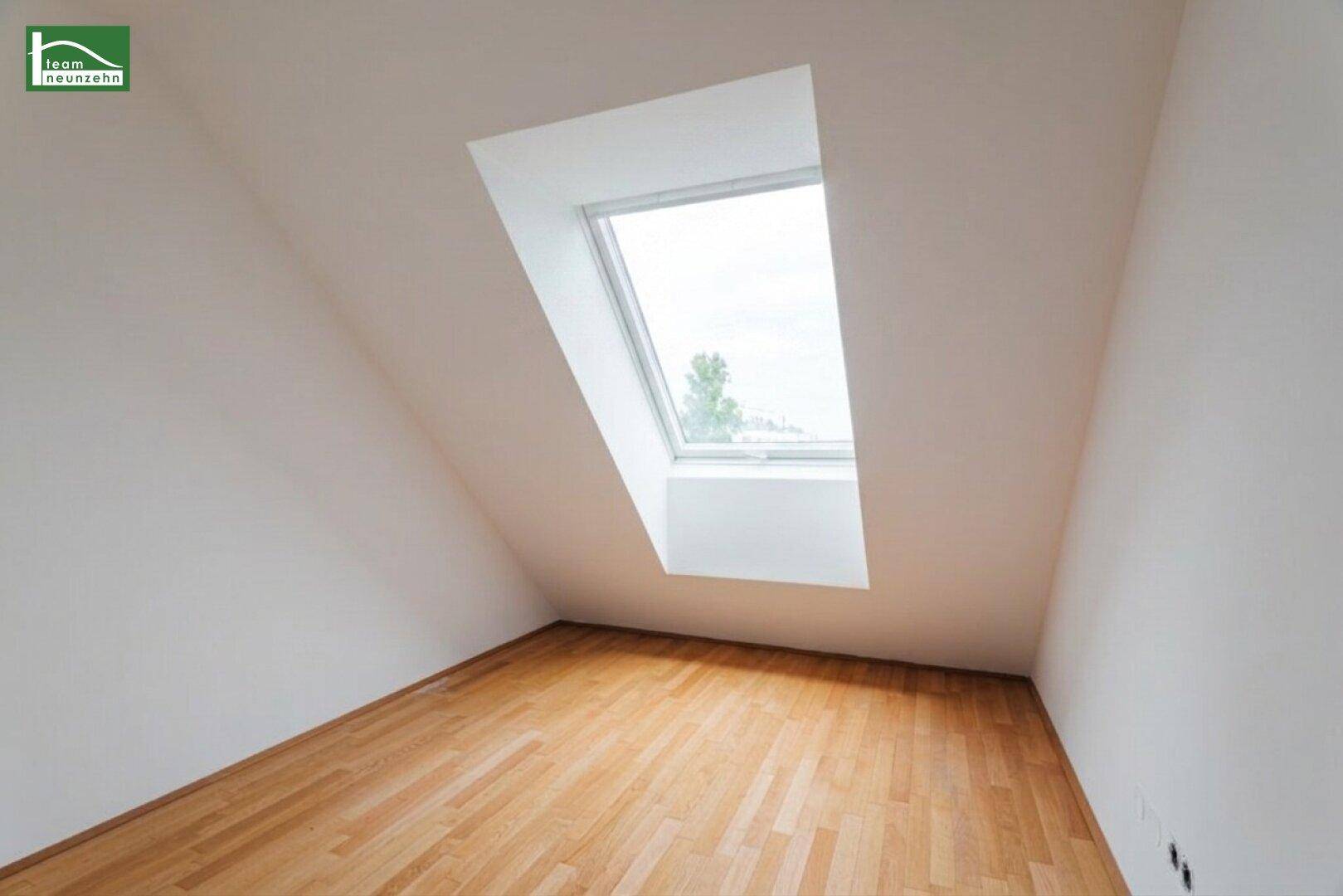 Kleineres Dachzimmer mit einem einzelnen Dachfenster und warmem Holzfußboden.