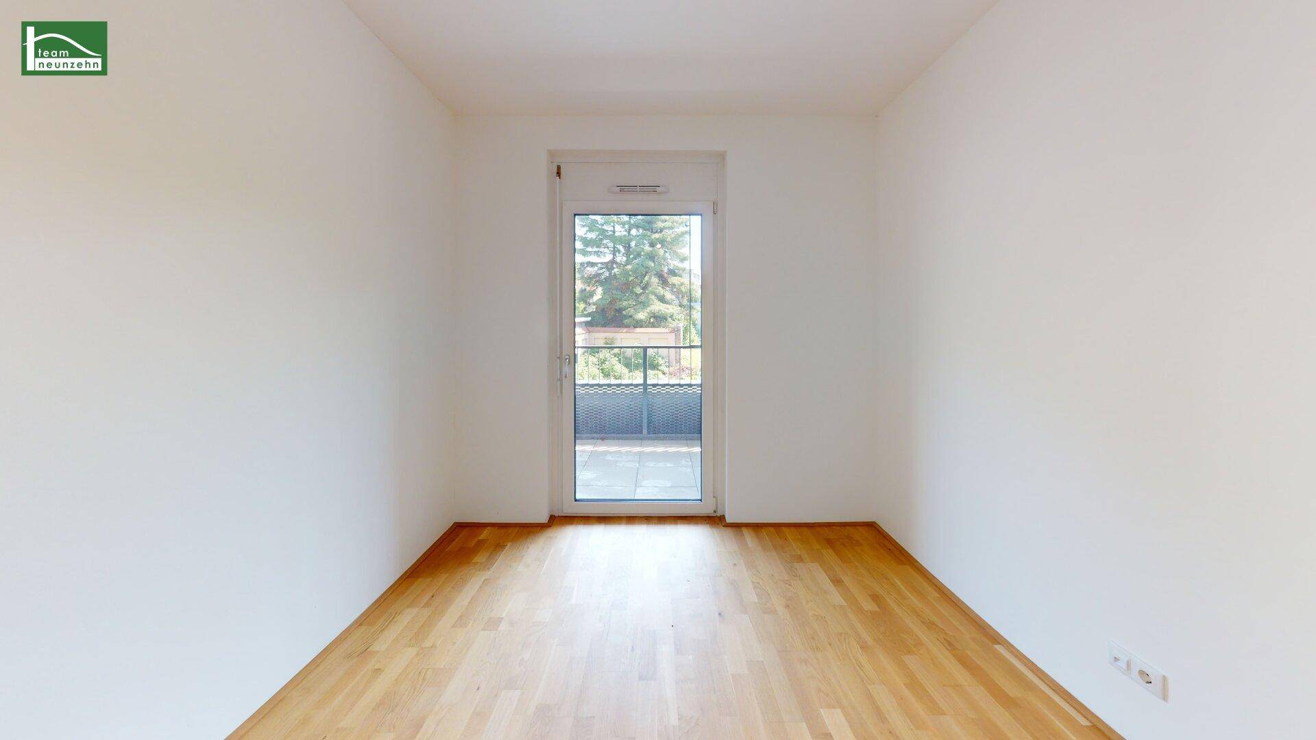 Heller Raum mit Parkettboden und bodentiefen Fenstern, die Zugang zum Balkon bieten.