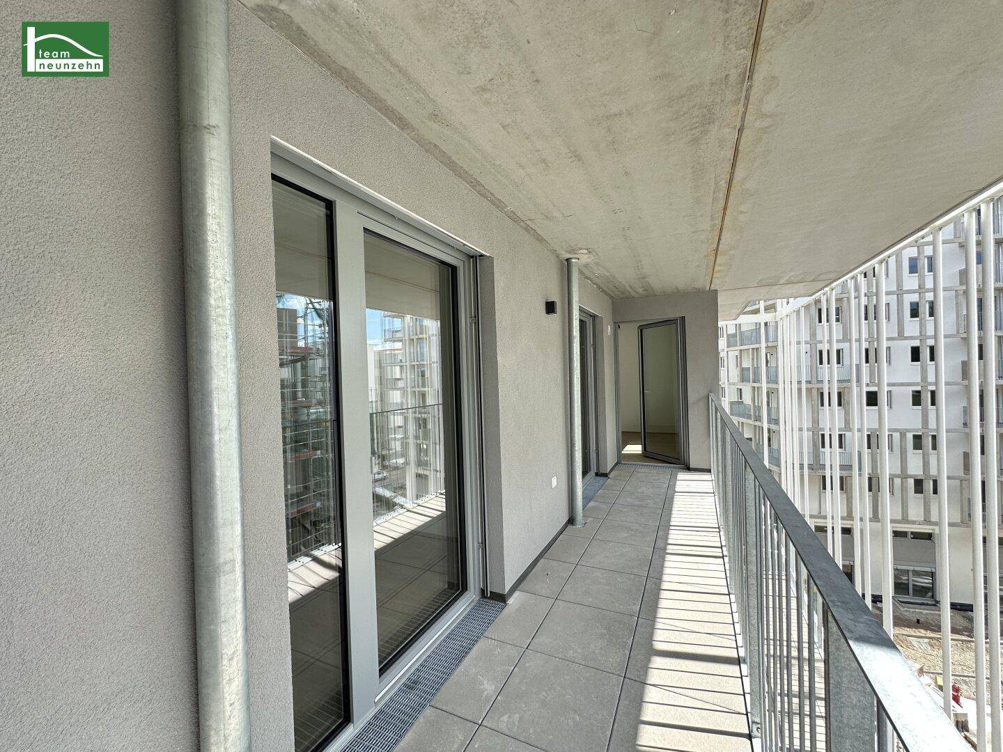 Moderner Balkon mit Schiebetüren und Fliesenboden, bietet Zugang zu den Innenräumen.