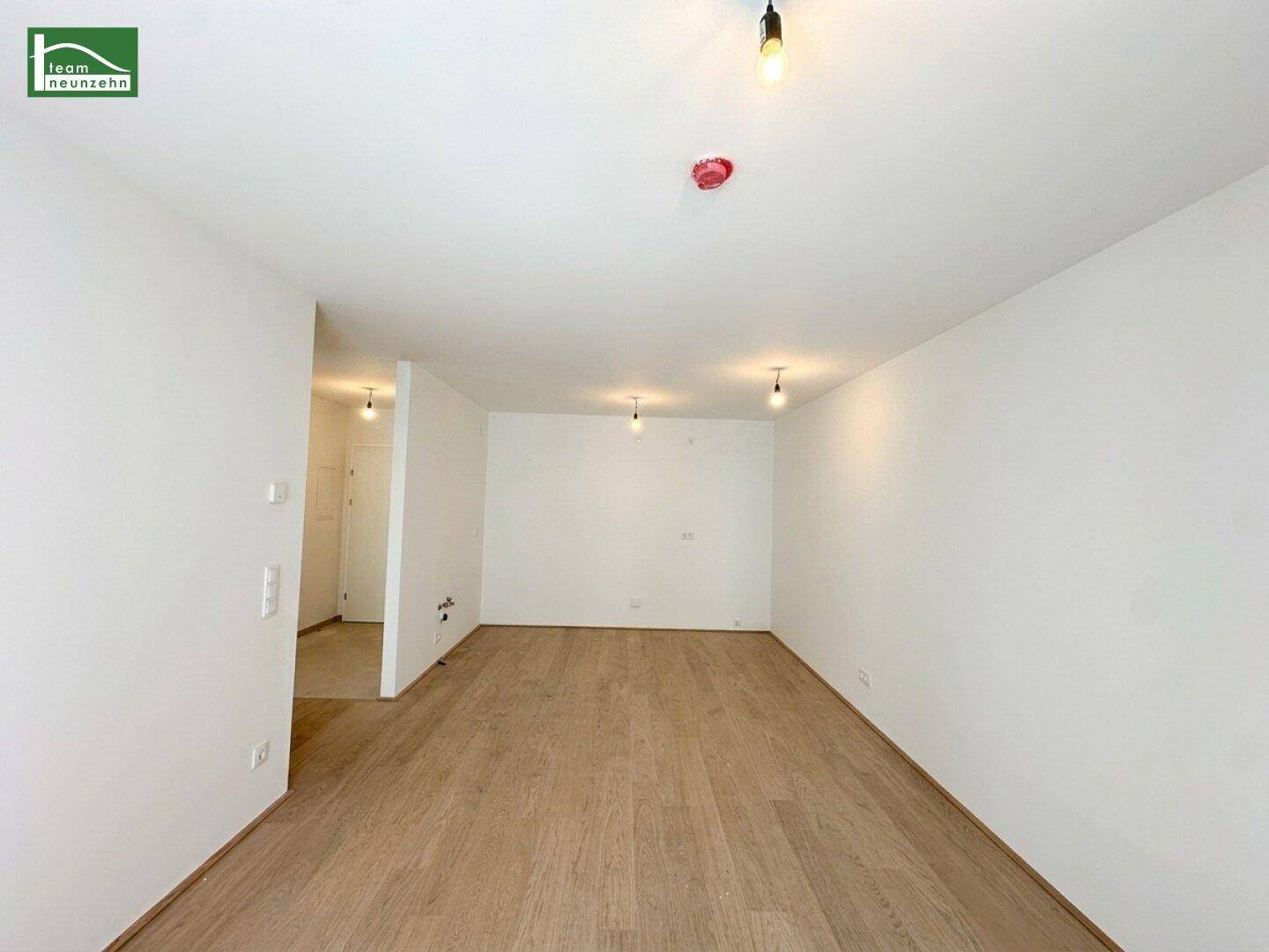Geräumiges, leeres Zimmer mit Holzboden und weiß gestrichenen Wänden, bereit zum Einzug.