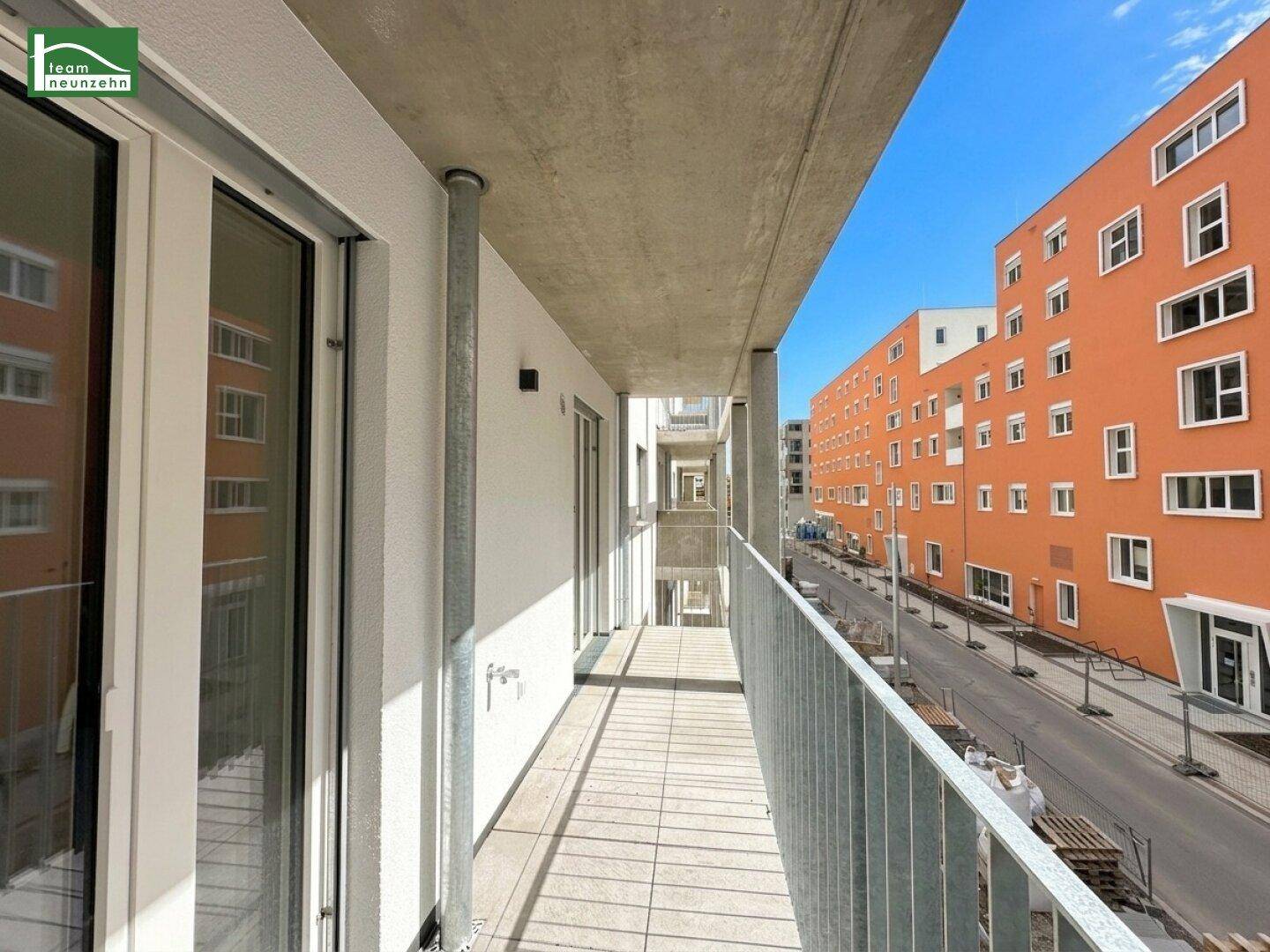 Überdachter Balkon mit Fliesenboden und Blick auf die umliegenden Neubauten.