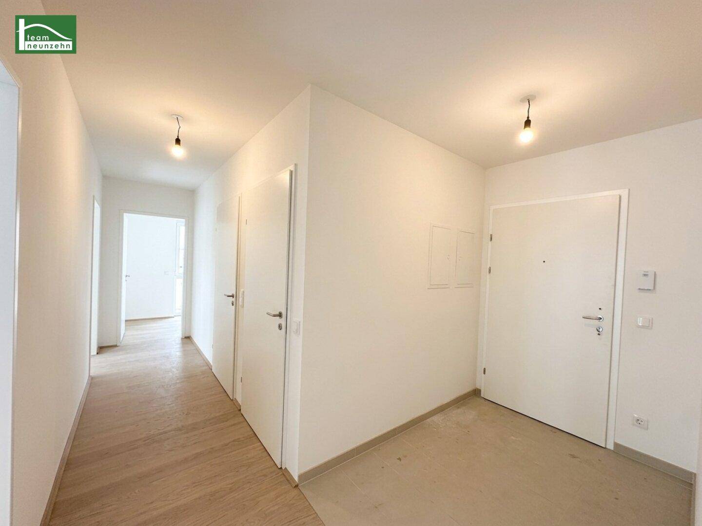 Heller Flur mit Holzboden und mehreren Türen, der zu verschiedenen Räumen führt.