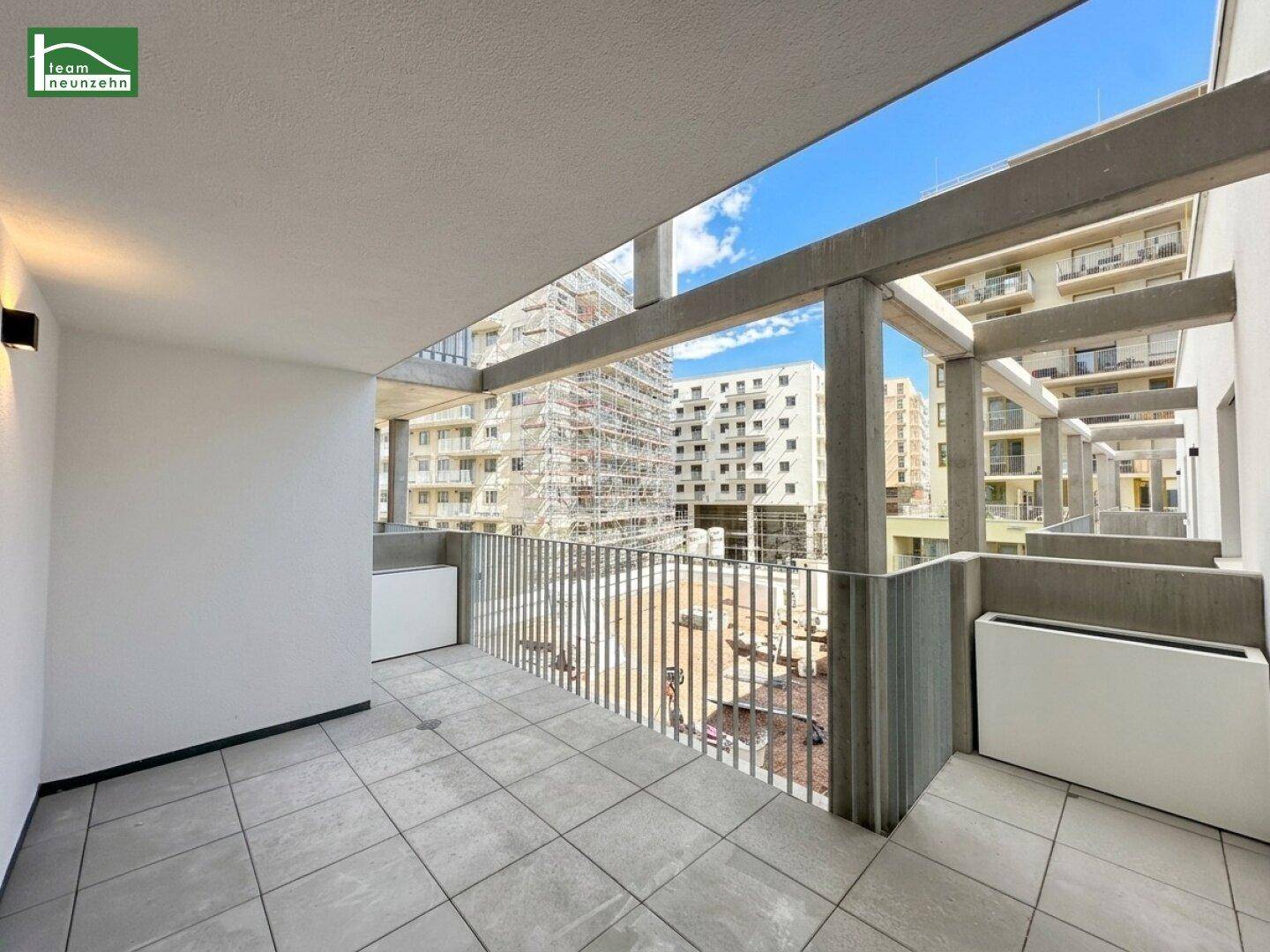 Moderner Balkon mit Fliesenboden und Blick auf die umliegenden Gebäude.