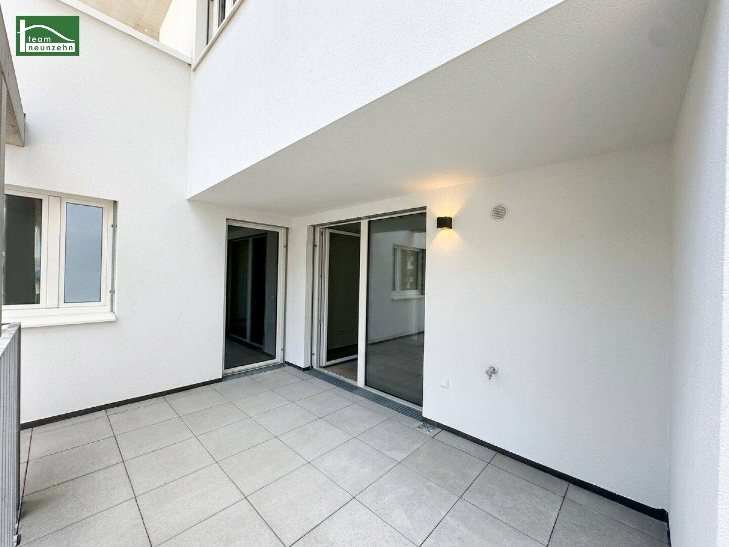 Heller Balkon mit Fliesenboden und Zugang zu den Innenräumen durch Schiebetüren.