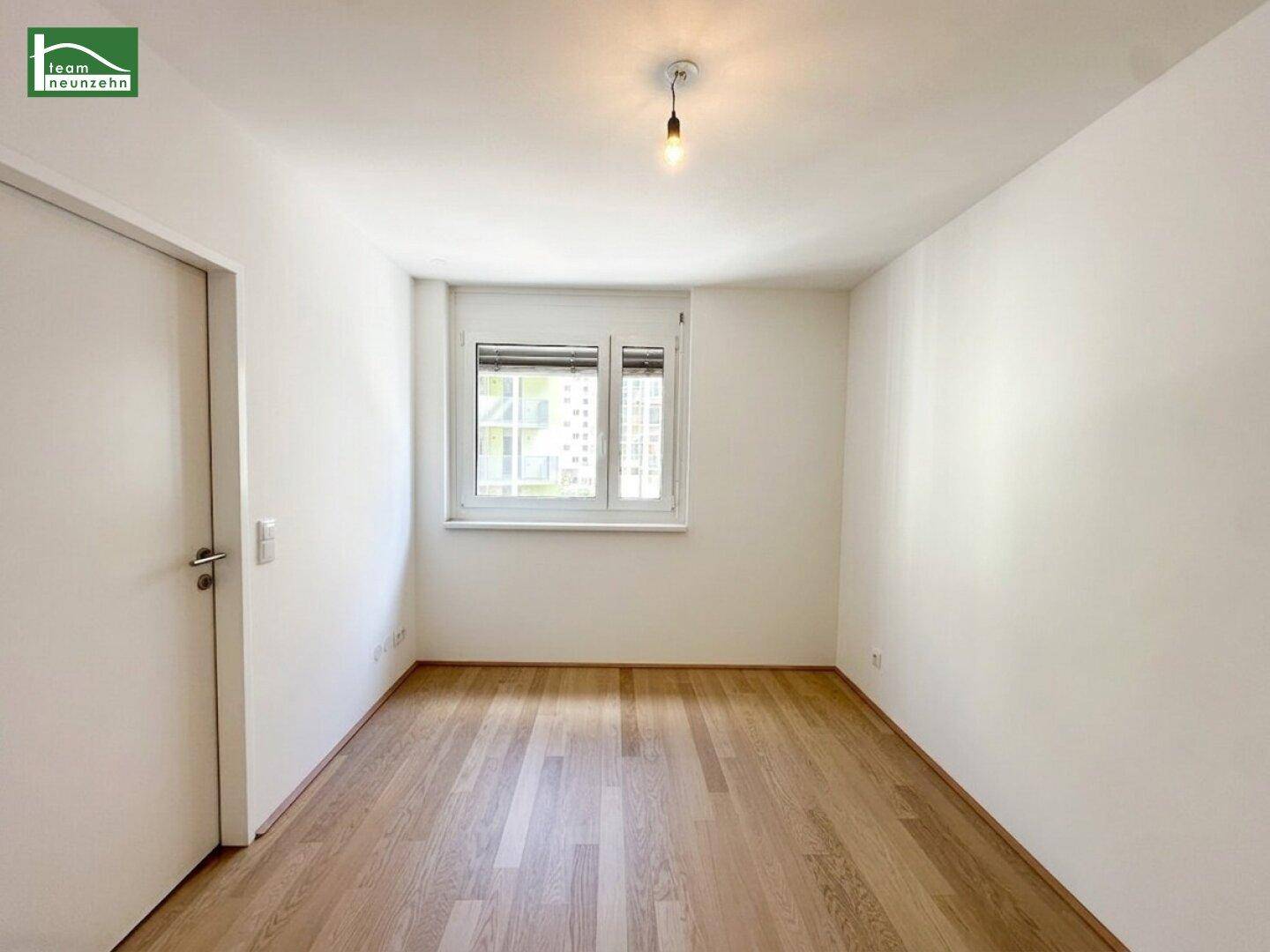 Helles Schlafzimmer mit Holzboden und einem Fenster, das viel Tageslicht hereinlässt.