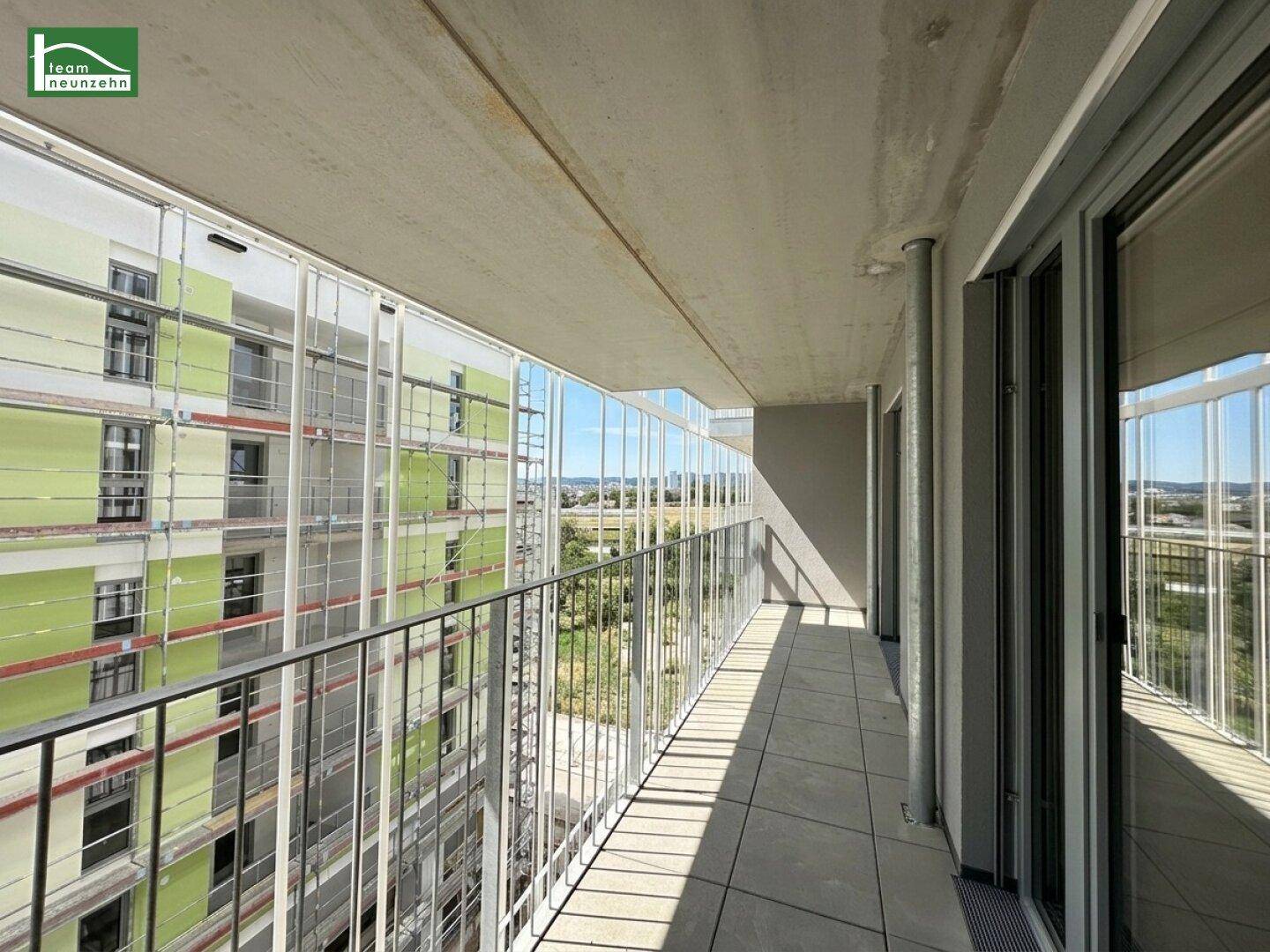 Langer Balkon mit Fliesenboden und Metallgeländer, bietet einen weiten Blick über die Umgebung.