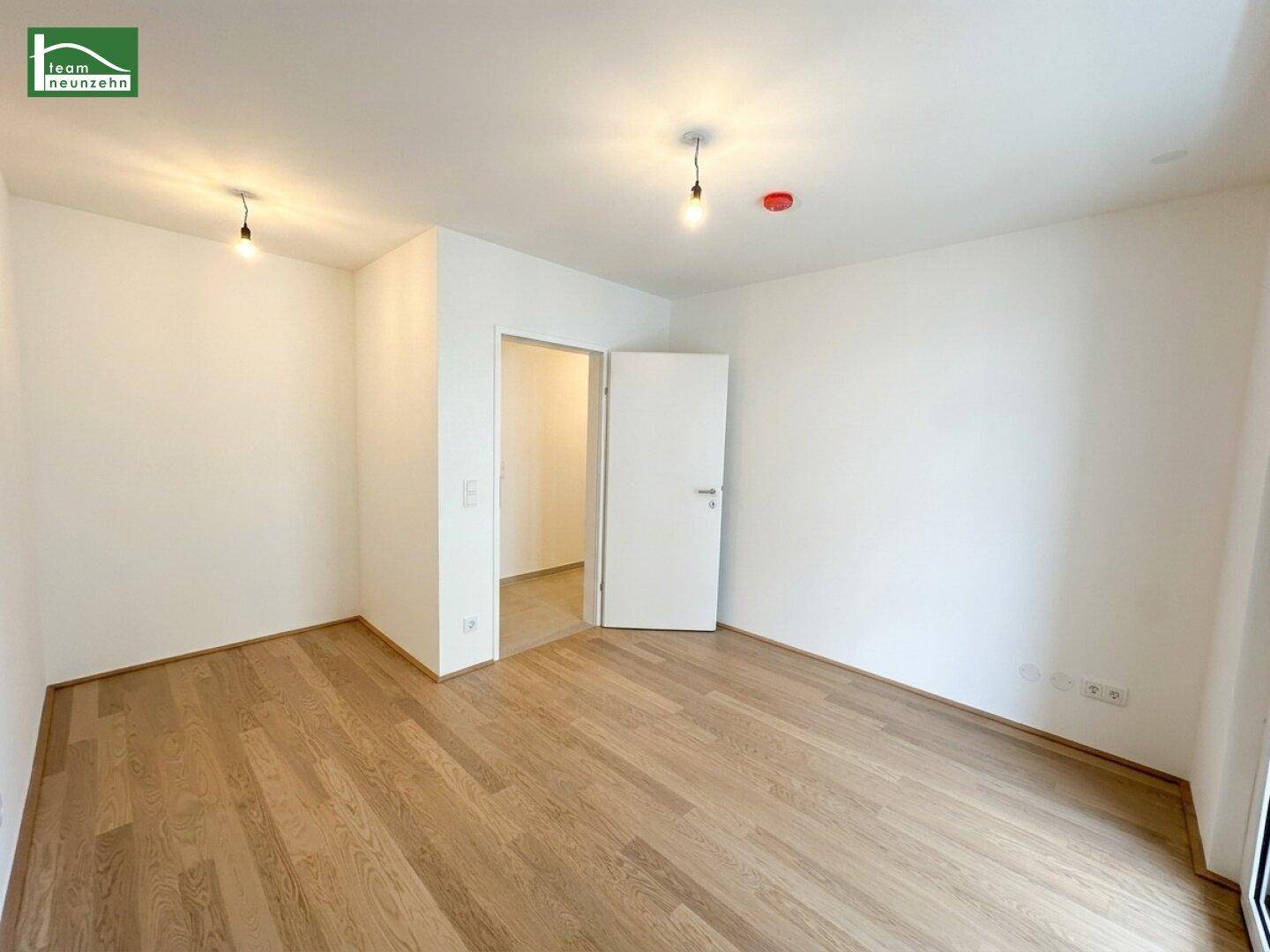 Unmöbliertes Zimmer mit hellem Parkettboden und weiß gestrichenen Wänden, bereit zur Einrichtung.