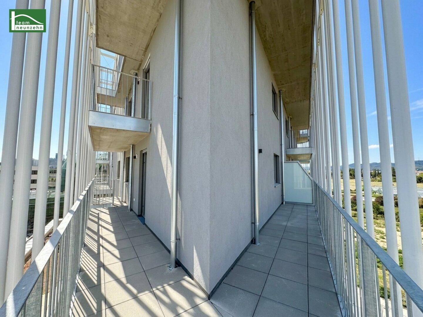 Langer Balkon mit Metallgeländer und Blick auf die Umgebung.