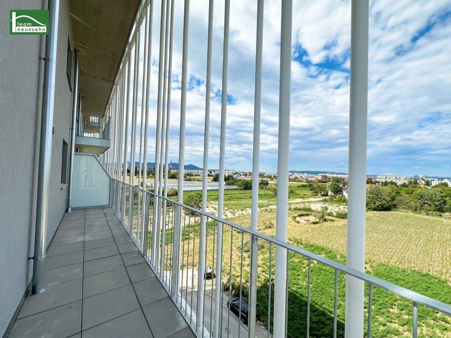 Geräumiger Balkon mit weitem Blick über grüne Felder und die Stadt.