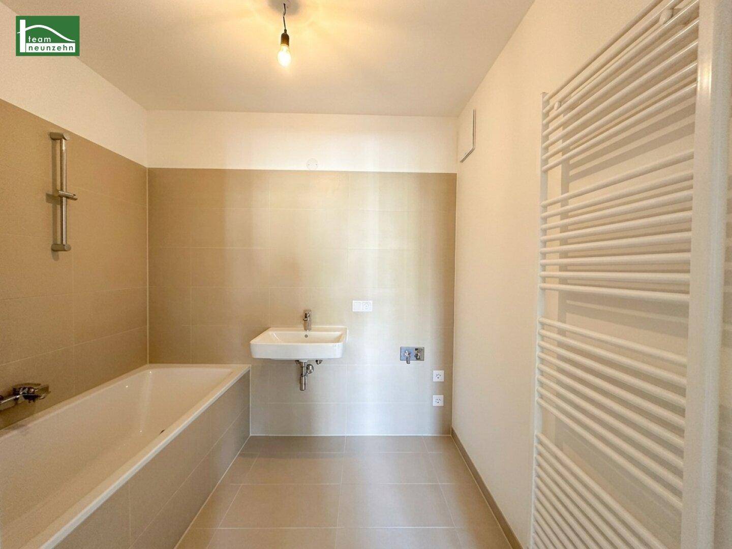 Modernes Badezimmer mit Badewanne, Waschbecken und beheiztem Handtuchhalter.