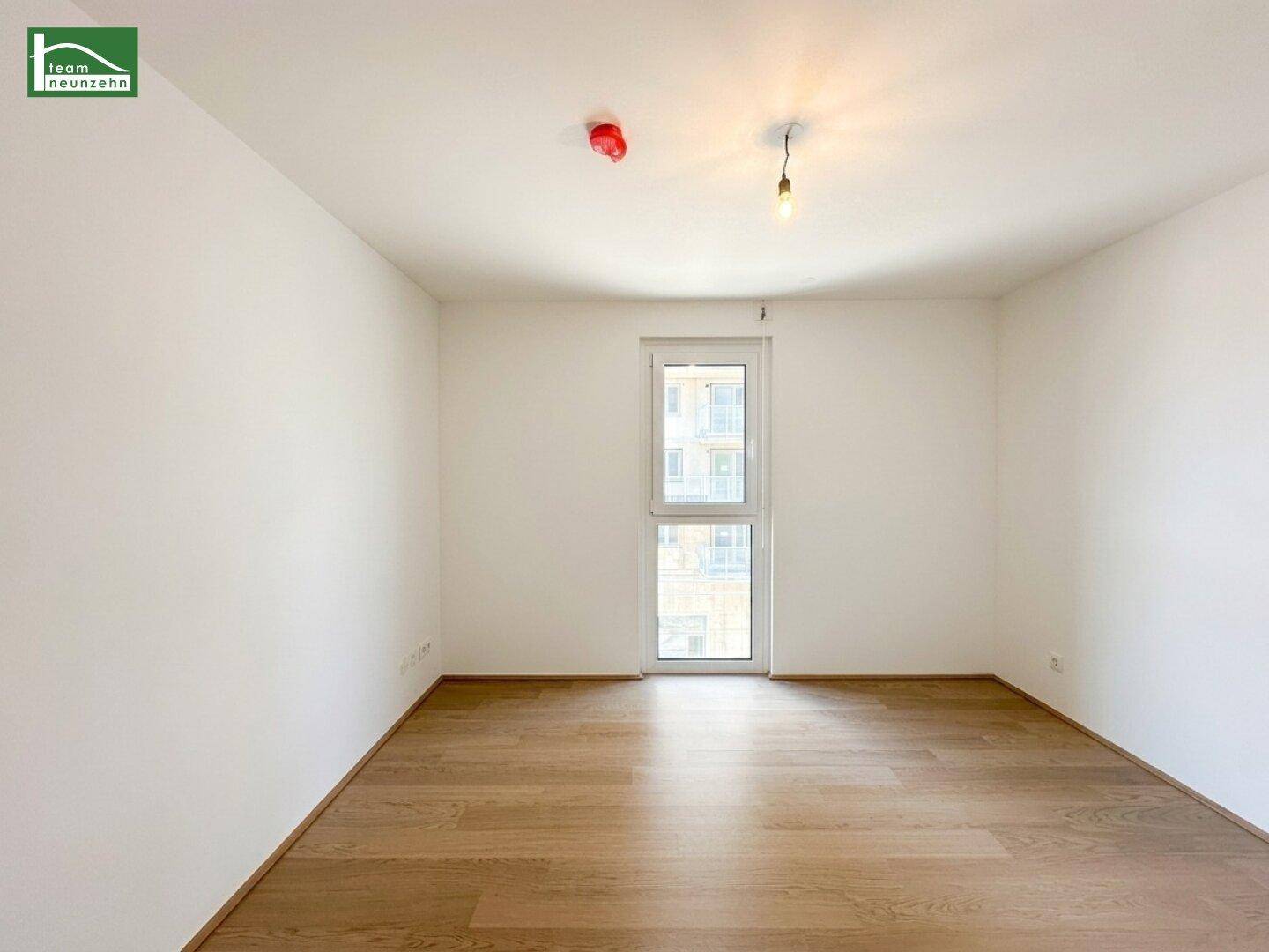 Helles Schlafzimmer mit Holzboden und einem großen Fenster, das viel natürliches Licht bietet.