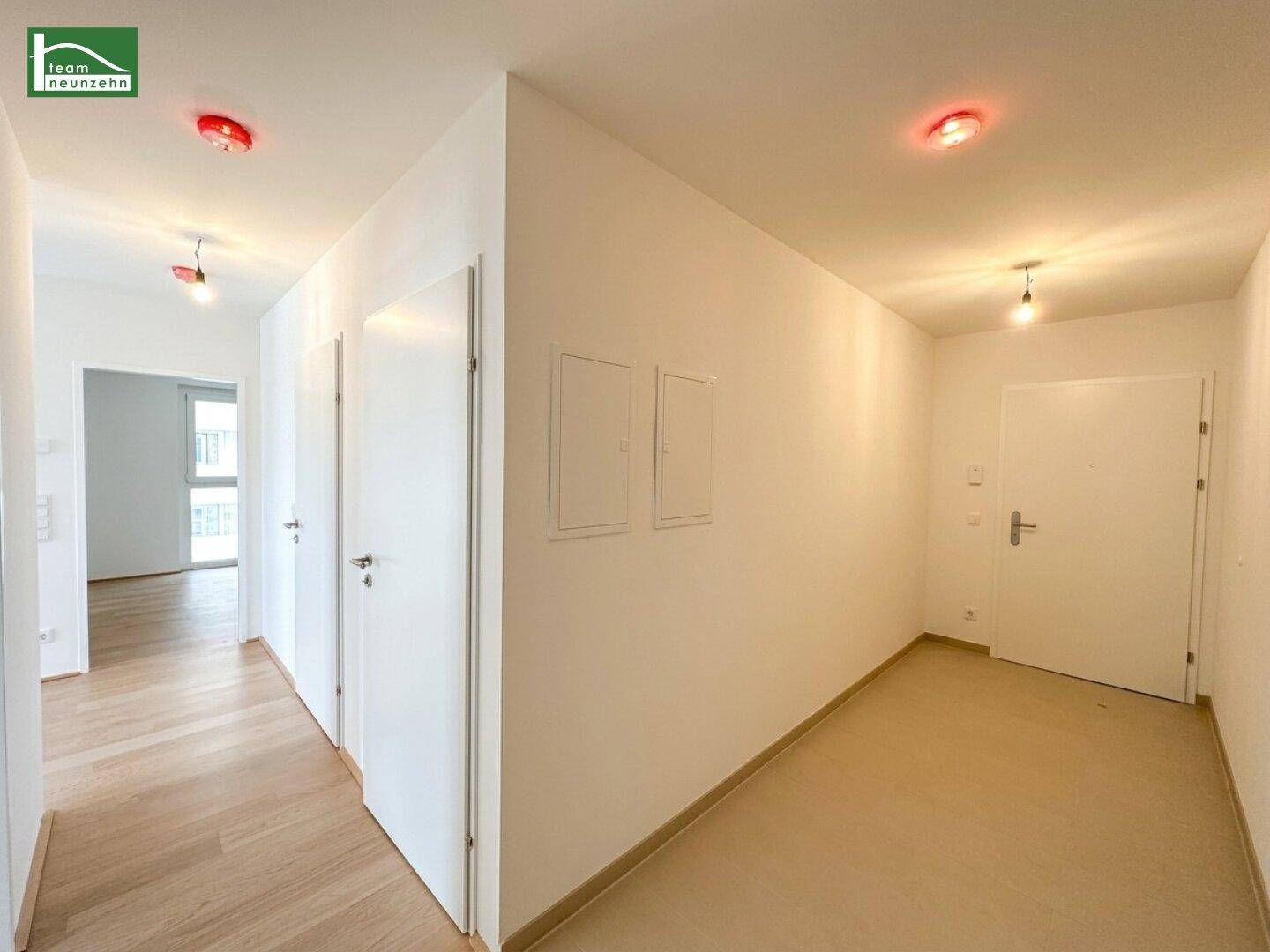 Heller Flur mit mehreren Türen und einem modernen Bodenbelag, der zu den Zimmern führt.