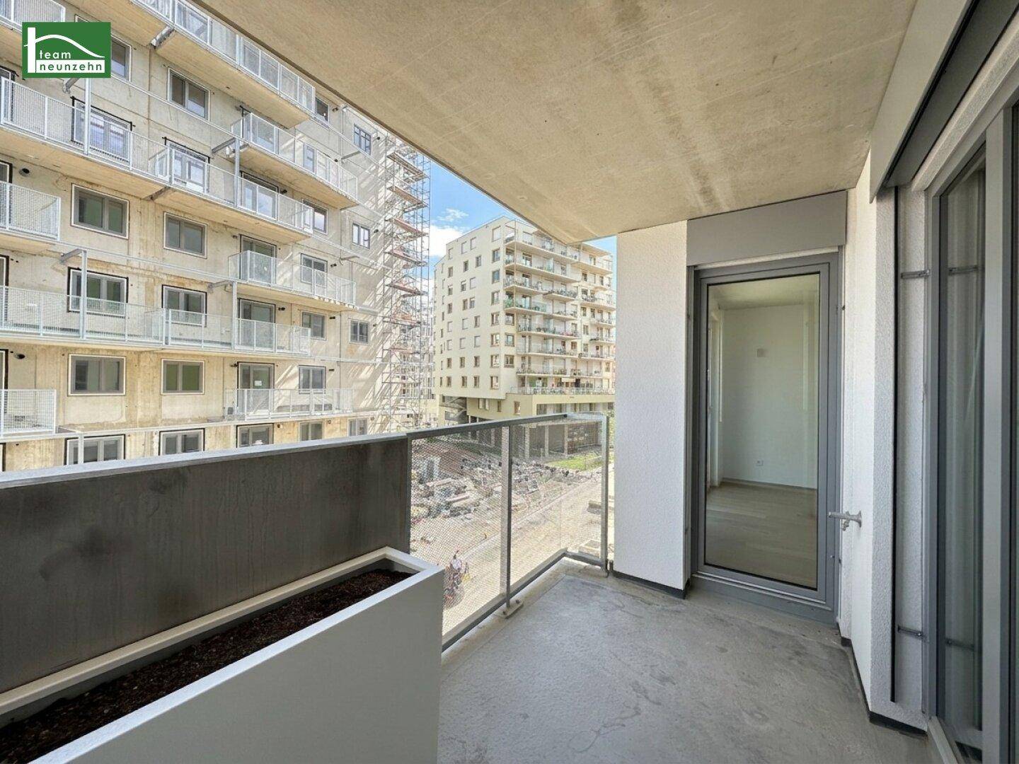 Balkon eines Neubaus mit Glasgeländer und Blick auf die umliegenden Gebäude und Baustellen.