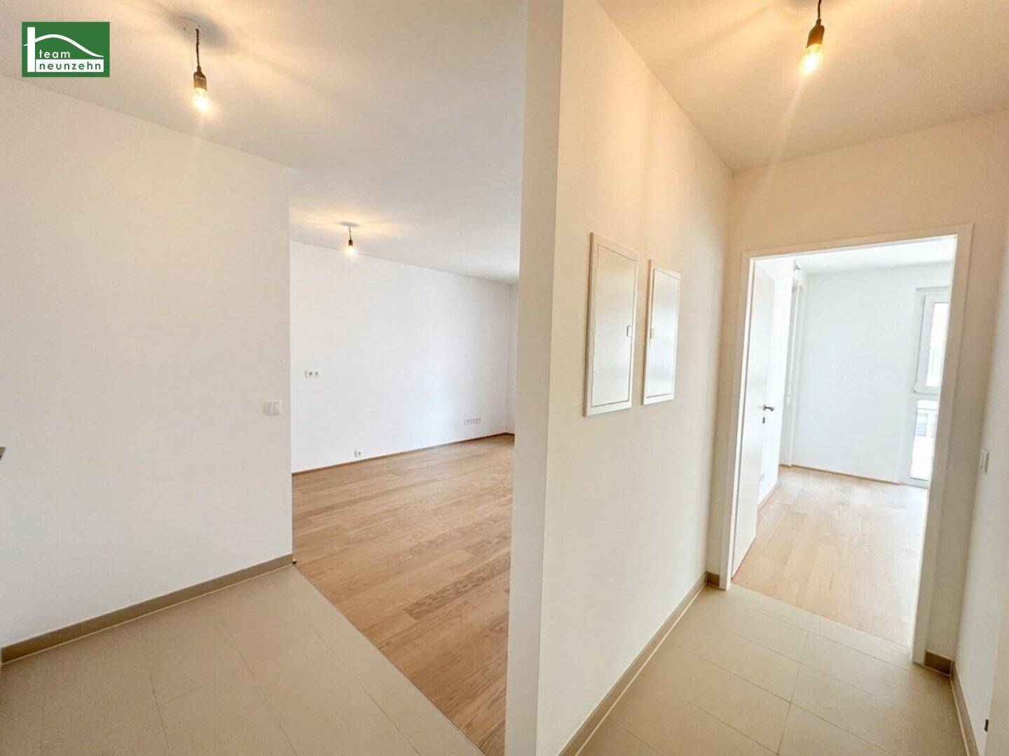 Heller Flur mit Fliesenboden, der zu weiteren Zimmern mit Holzboden führt.