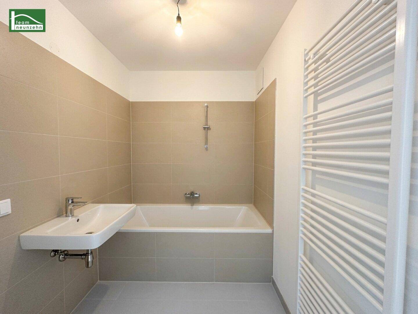 Modernes Badezimmer mit Badewanne, Waschbecken und beheiztem Handtuchhalter.