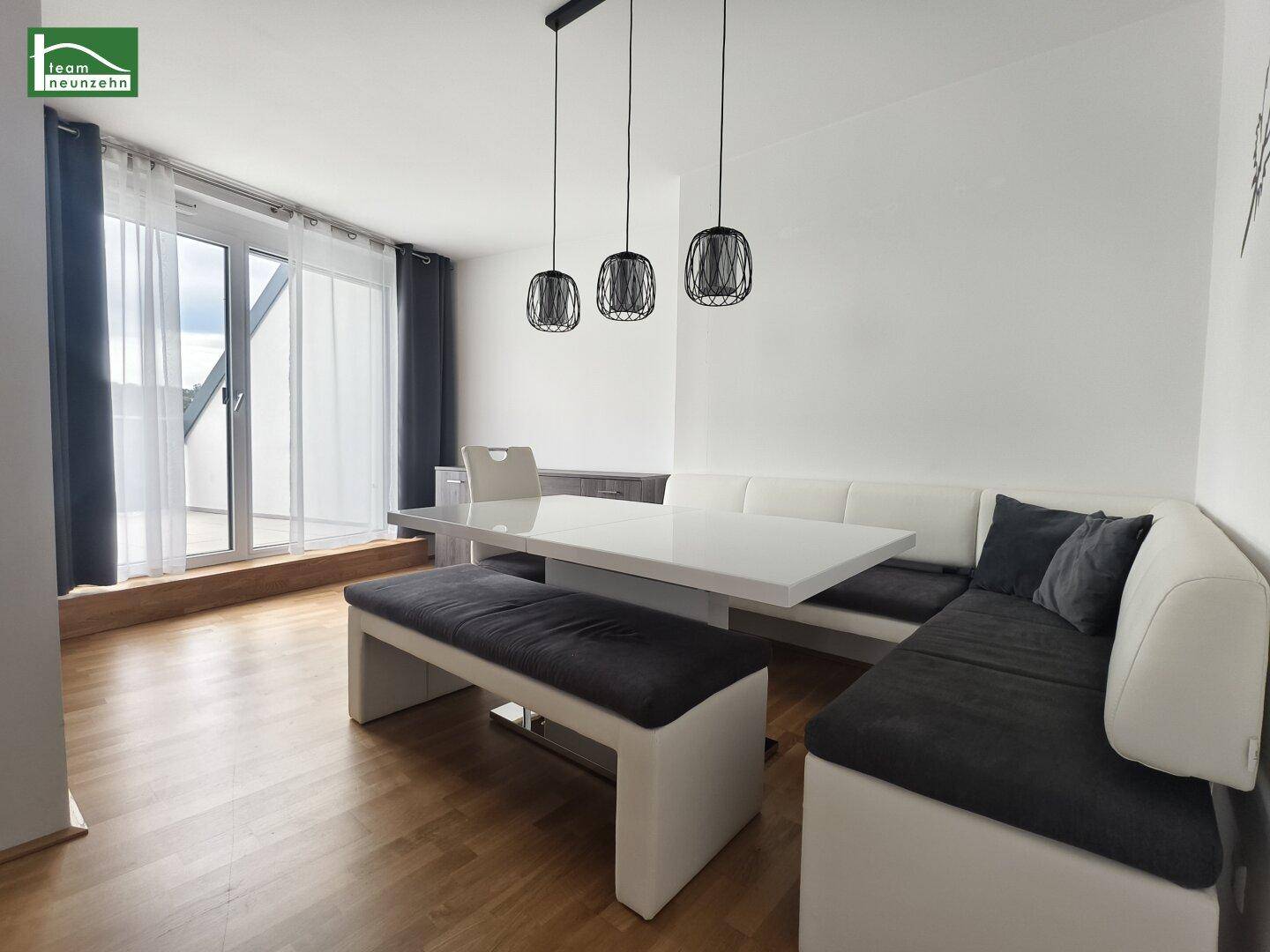 Heller Essbereich mit Eckbank, Esstisch und Zugang zu einem Balkon.