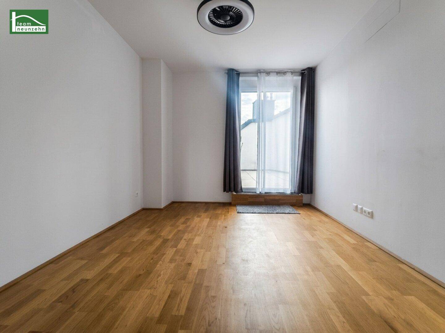 Leeres Schlafzimmer mit Holzboden und Zugang zu einem Balkon, bereit zur Einrichtung.