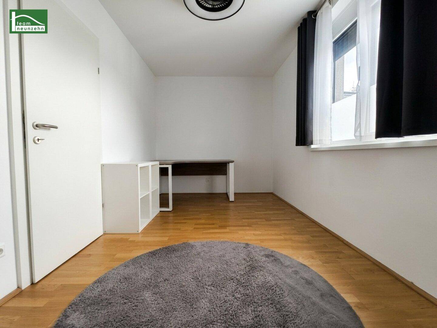 Helles Arbeitszimmer mit Holzboden und einem Schreibtisch am Fenster.