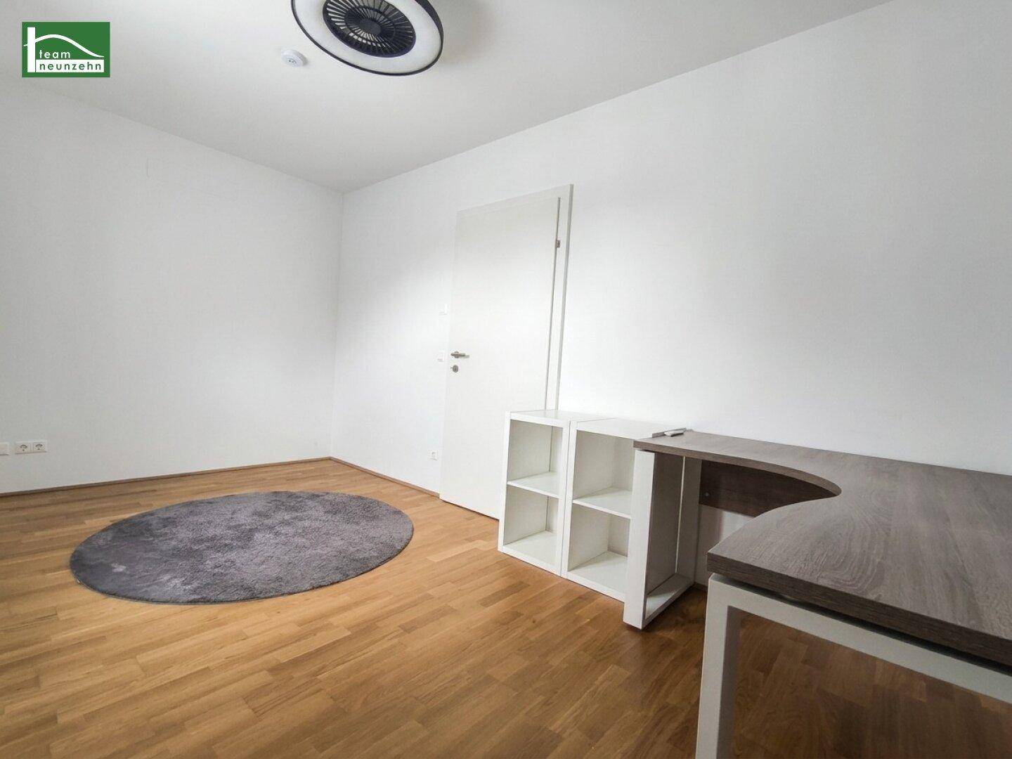 Arbeitszimmer mit Holzboden, weiß gestrichenen Wänden und einem modernen Schreibtisch.