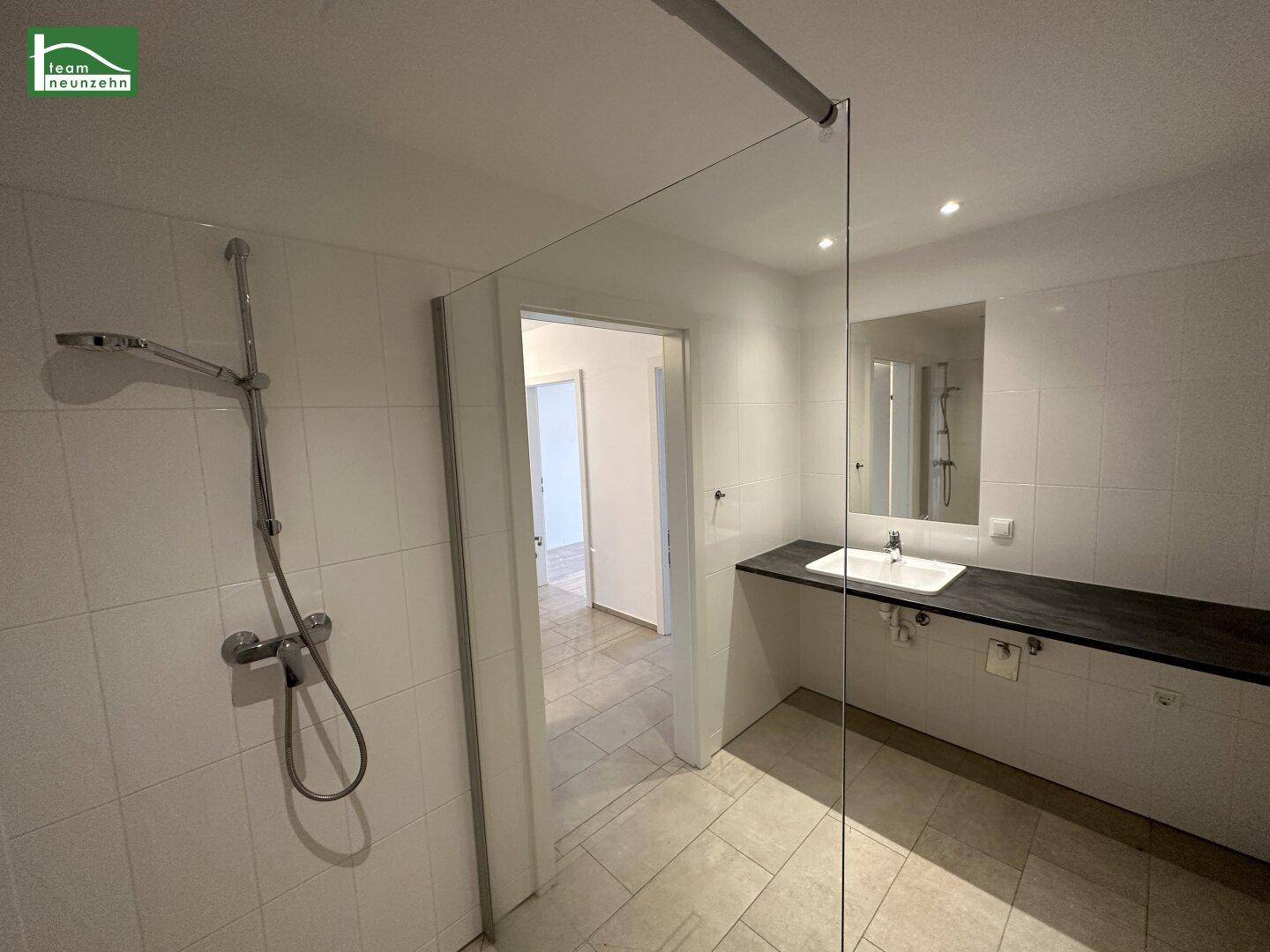 Modernes Badezimmer mit weiß gefliestem Boden, Dusche und Einzelwaschbecken.