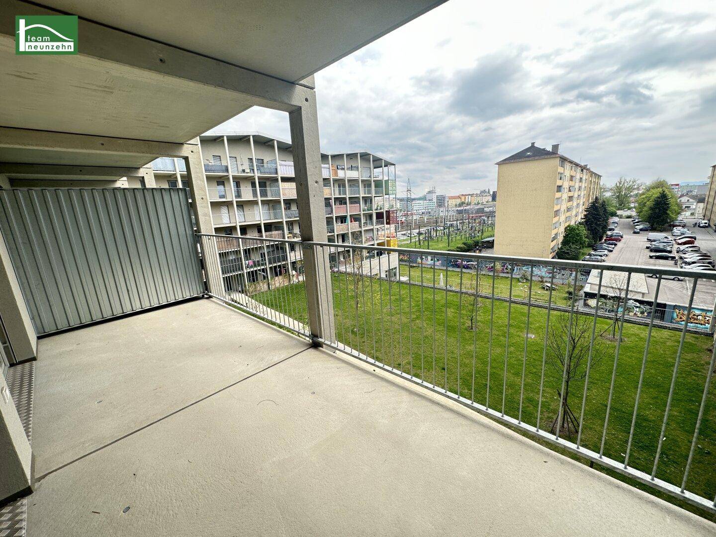 Geräumiger Balkon mit Blick auf eine Grünfläche und umliegende Wohngebäude.