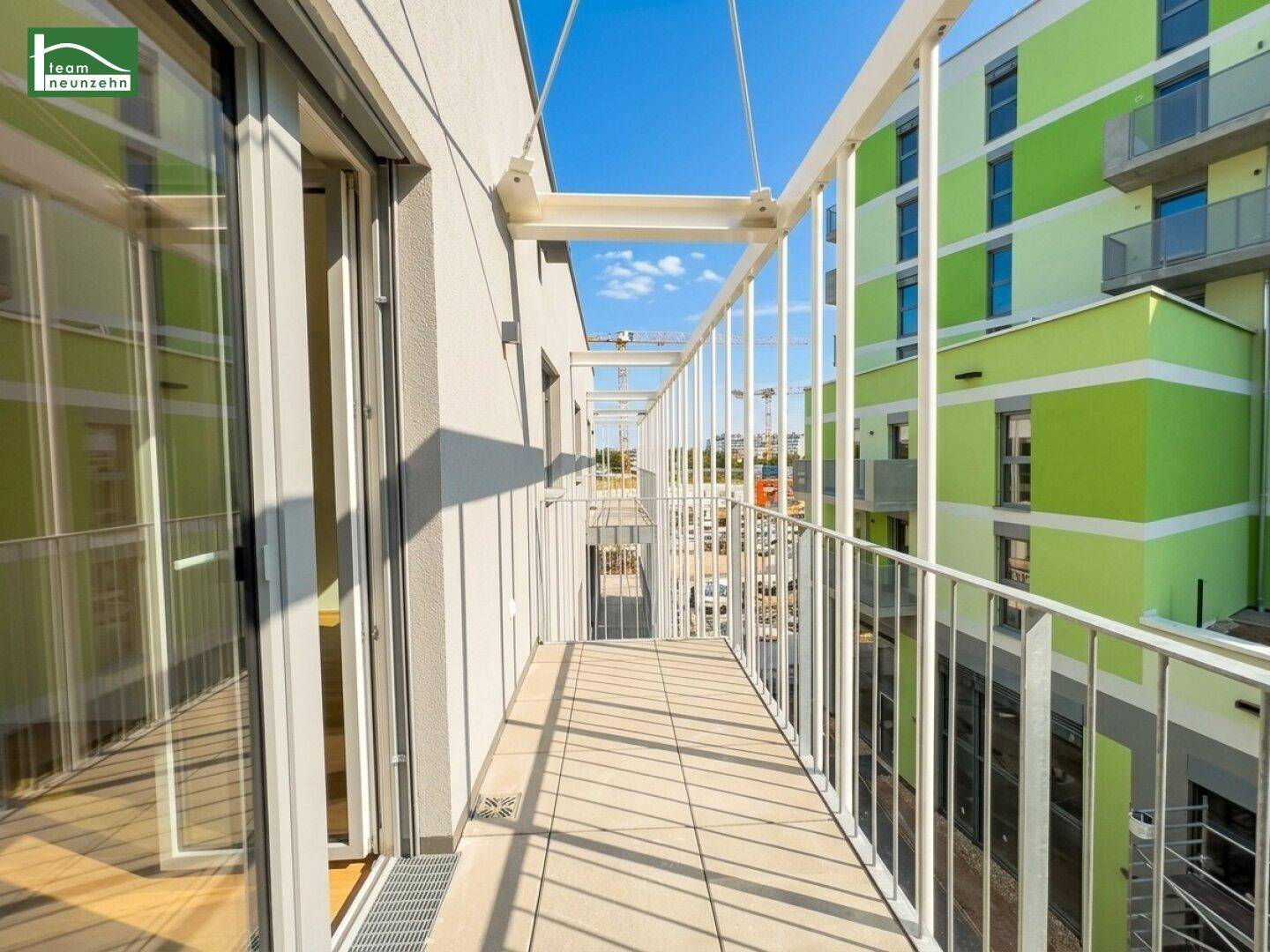 Langer, schmaler Balkon mit Fliesenboden und Blick auf die umliegenden Gebäude.