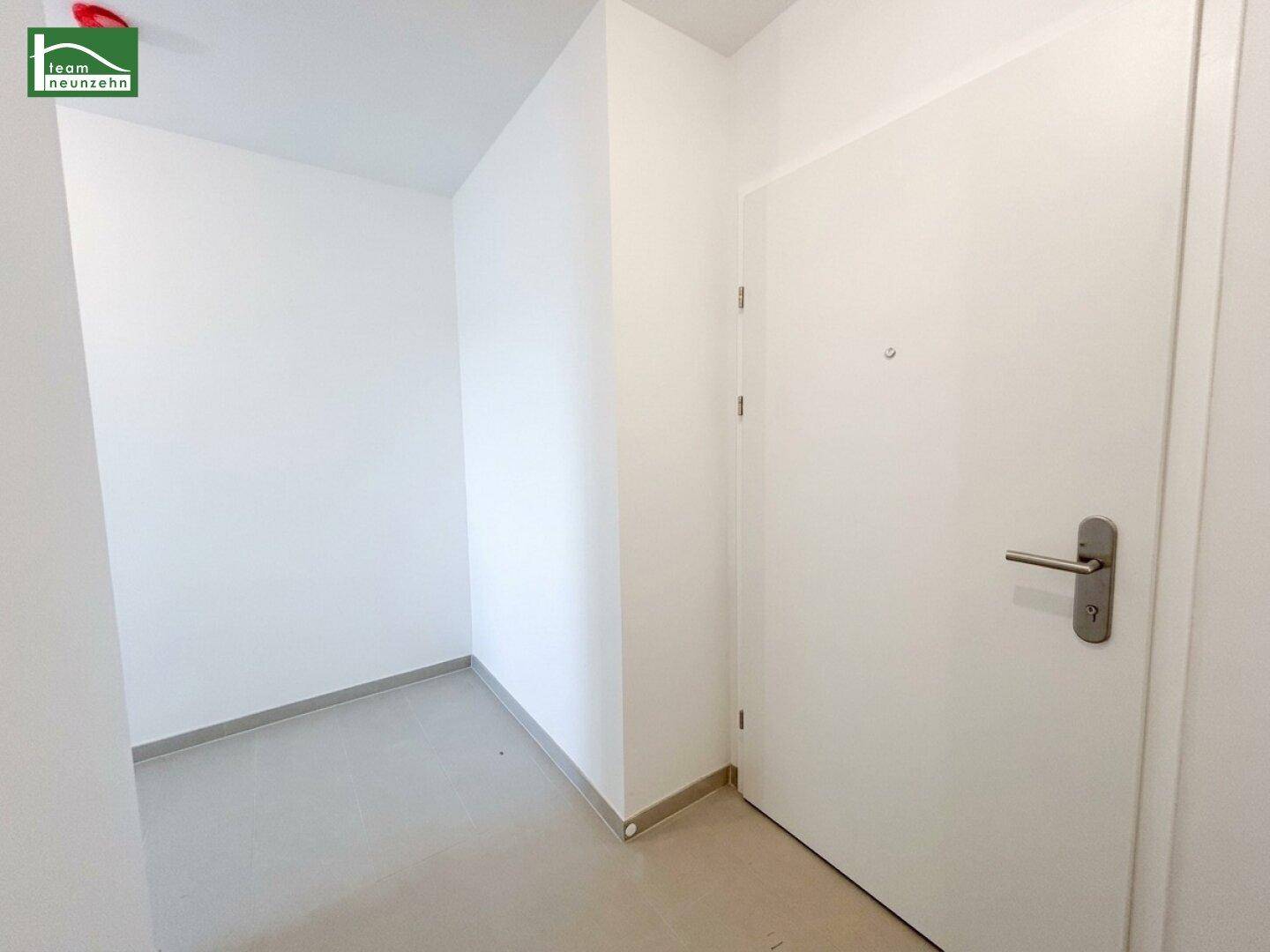 Eingangsbereich mit weißer Tür und Fliesenboden in einem modernen und gepflegten Zustand.