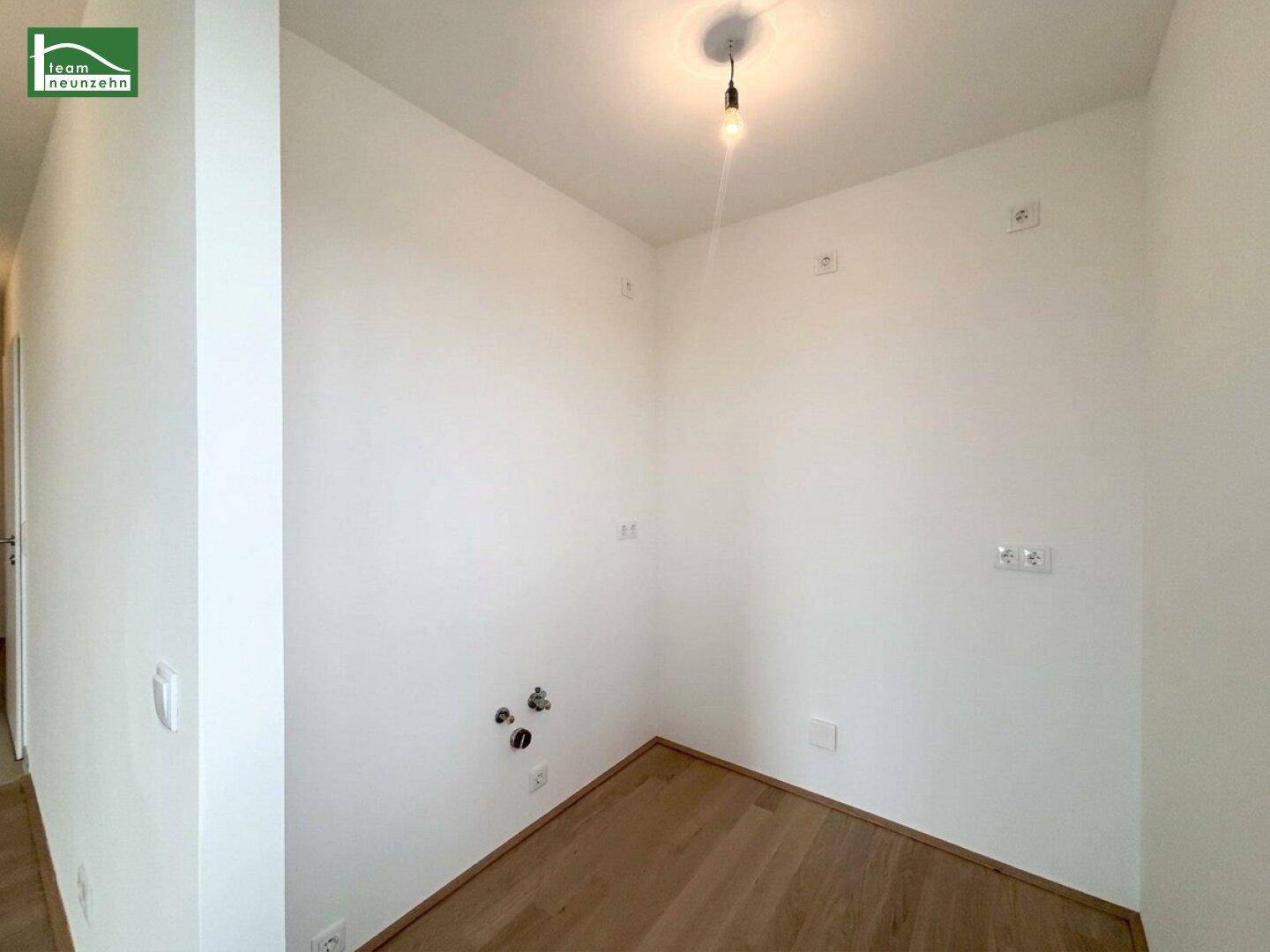 Kleiner Hauswirtschaftsraum mit Anschlüssen für Waschmaschine und hellem Holzboden.