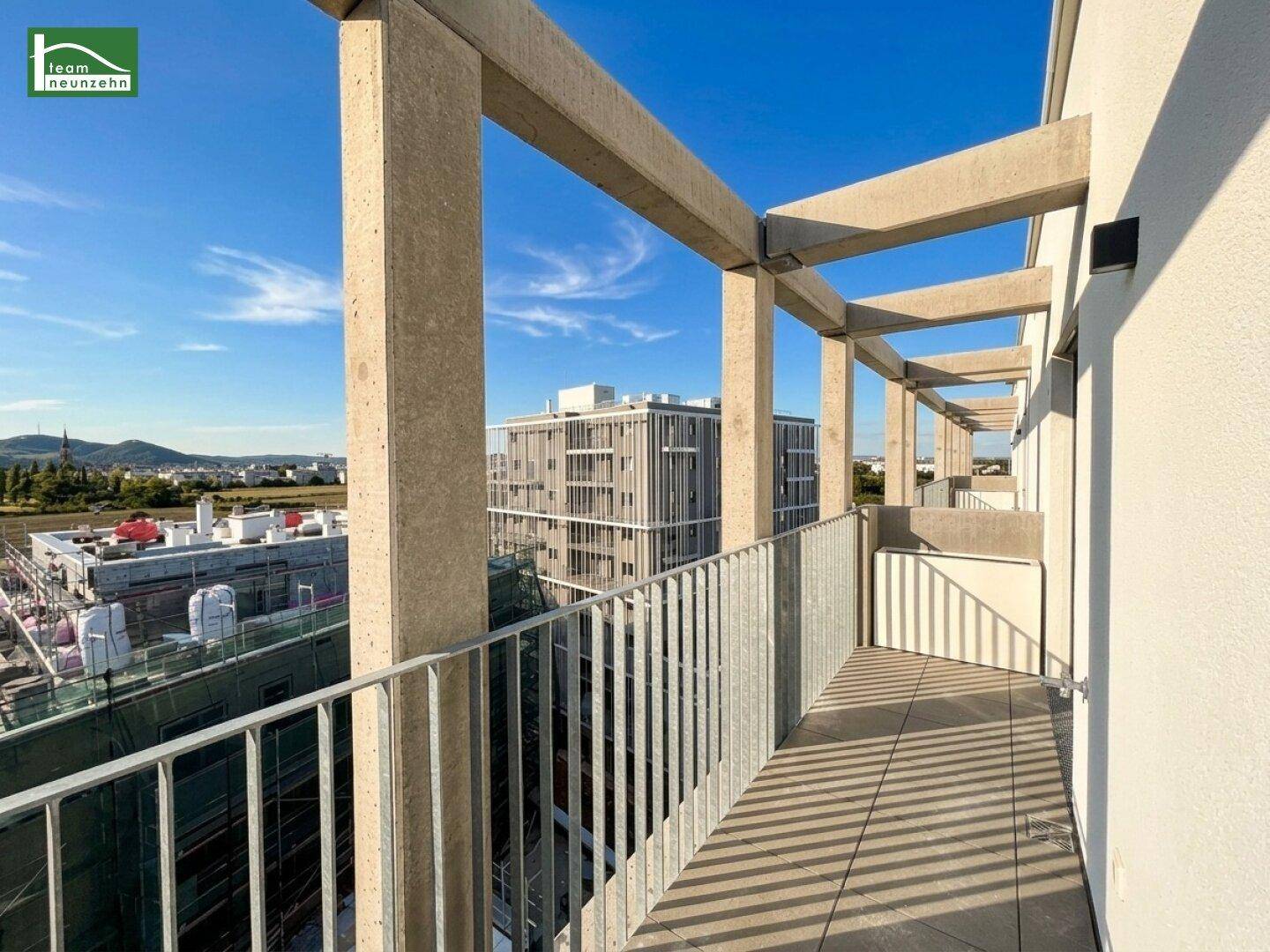 Geräumige Terrasse mit moderner Betonstruktur und Blick auf umliegende Neubauten.