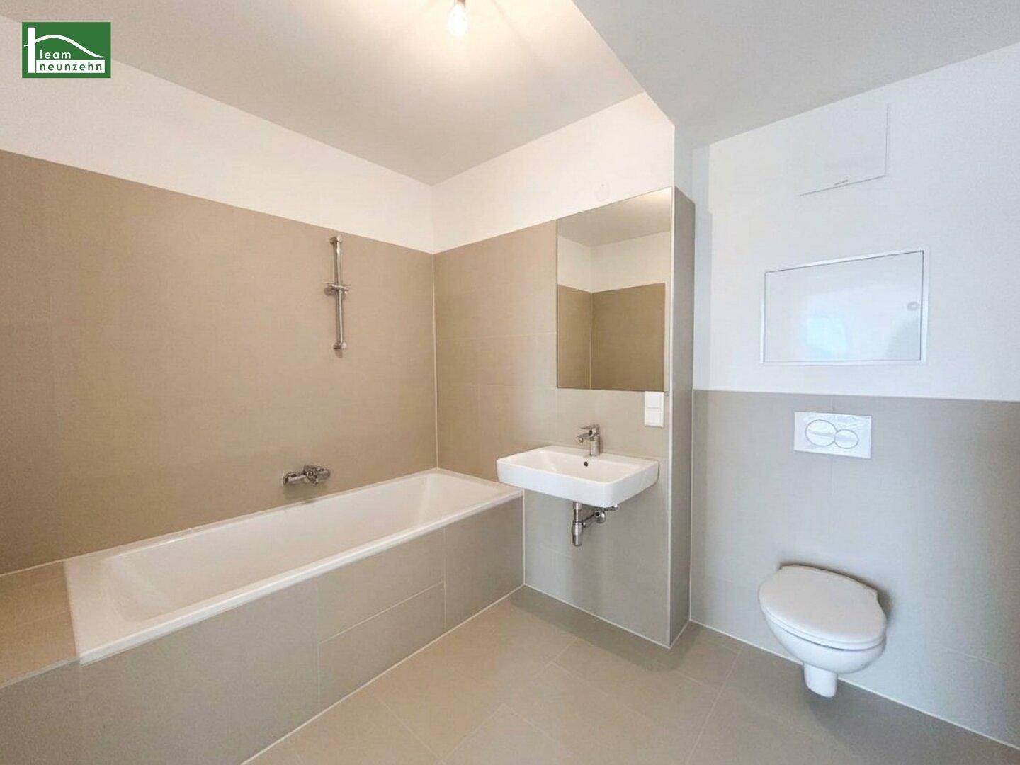 Modernes Badezimmer mit Badewanne, wandhängendem WC und beigefarbenen Fliesen.