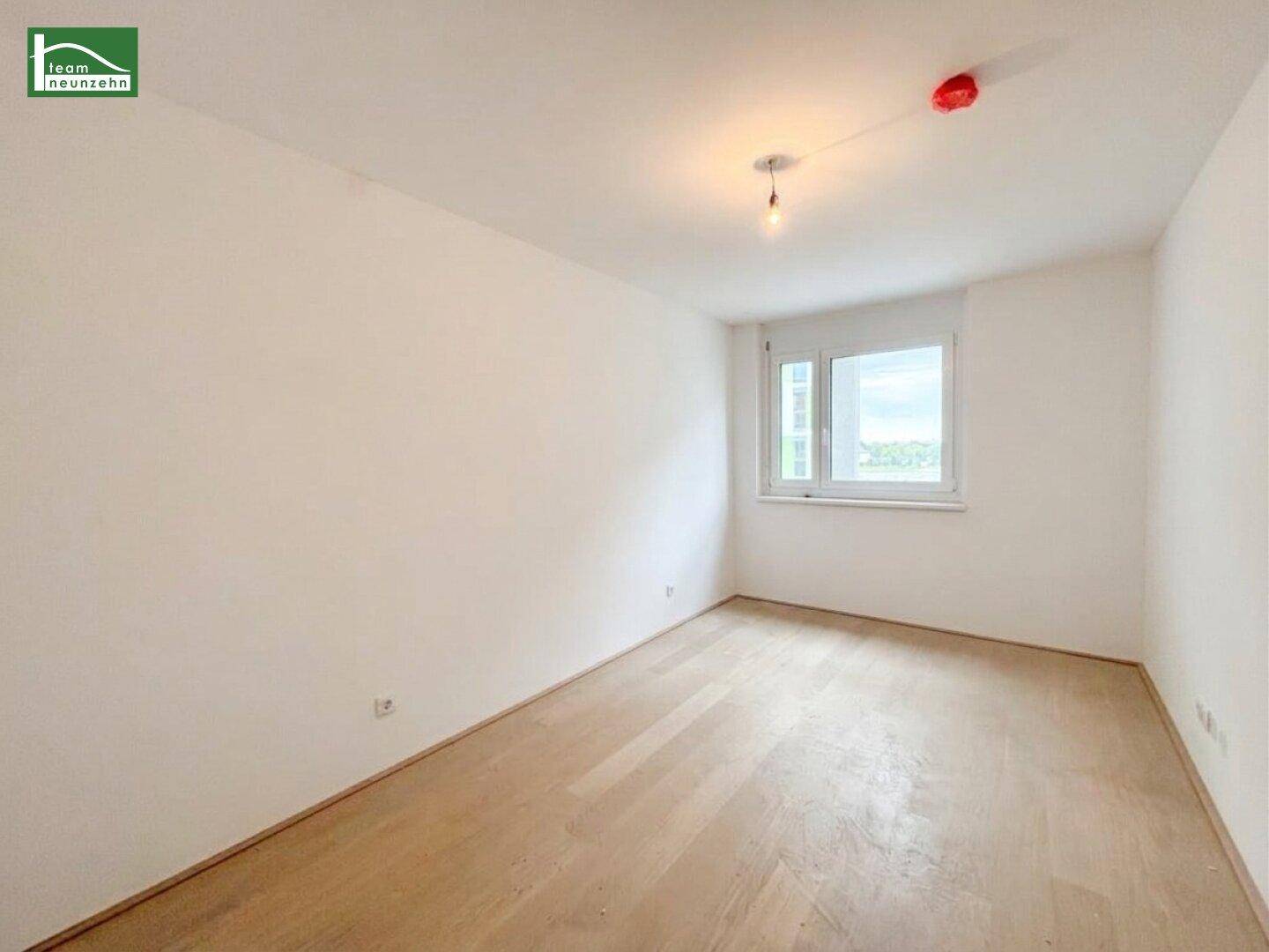 Ruhiges Schlafzimmer mit hellem Holzboden und einem Fenster, ideal für persönliche Gestaltung.
