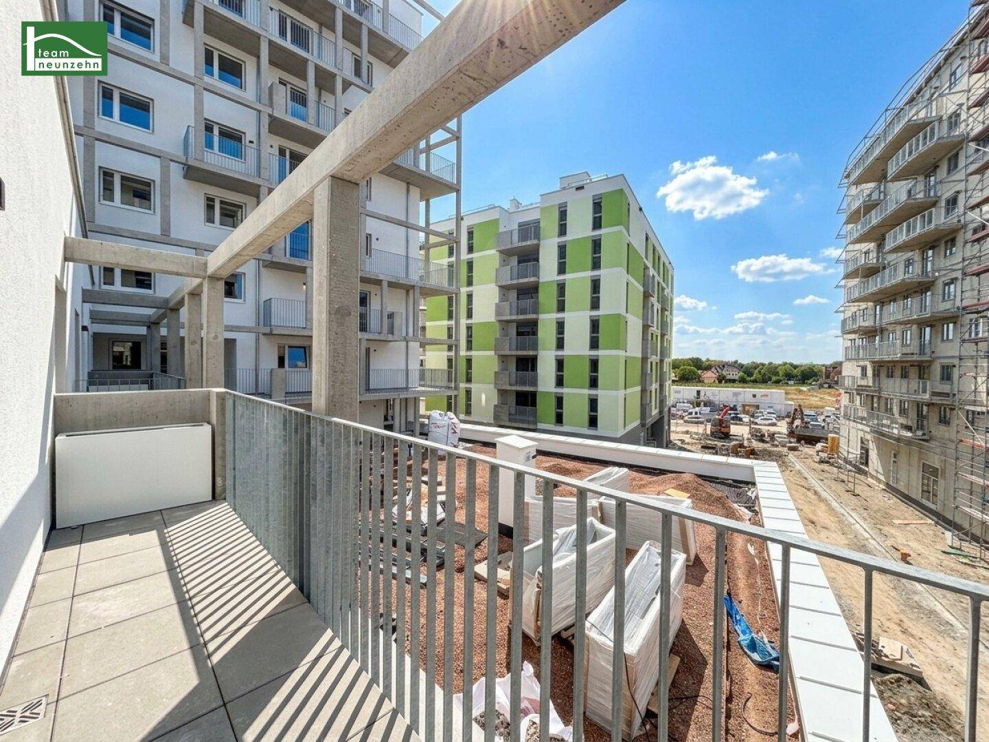 Sonniger Balkon eines Neubaus mit Blick auf weitere im Bau befindliche Gebäude.