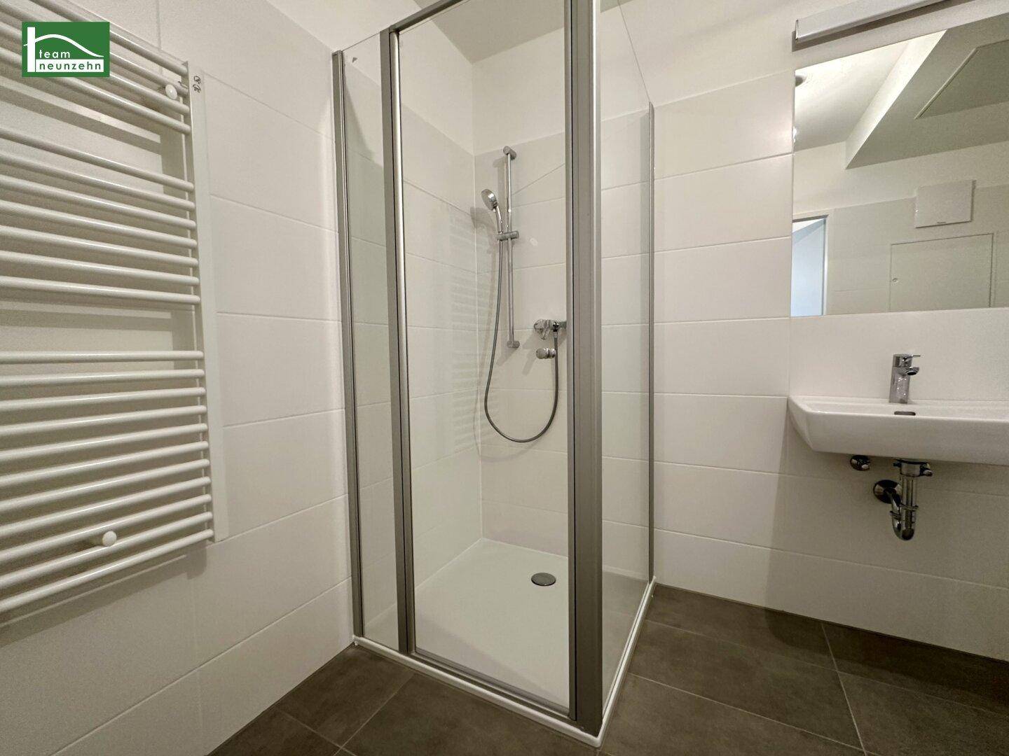 Modernes Badezimmer mit Duschkabine, Waschbecken und praktischem beheiztem Handtuchhalter.