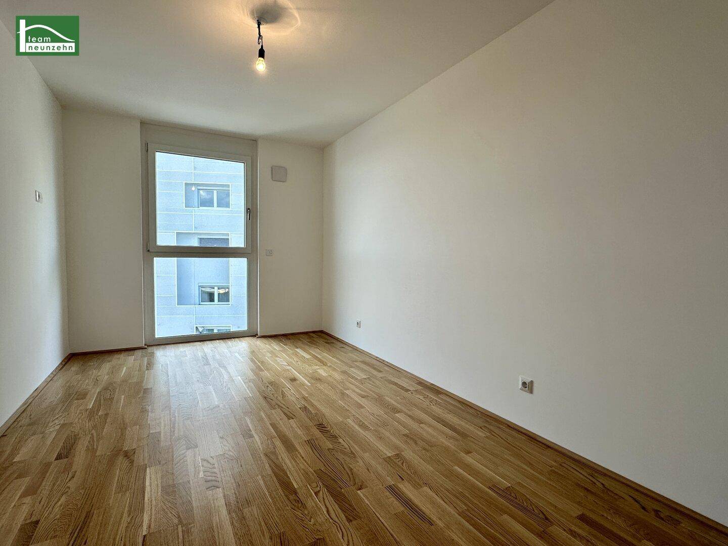 Leeres Zimmer mit Parkettboden und großem Fenster, ideal als Schlafzimmer oder Büro nutzbar.