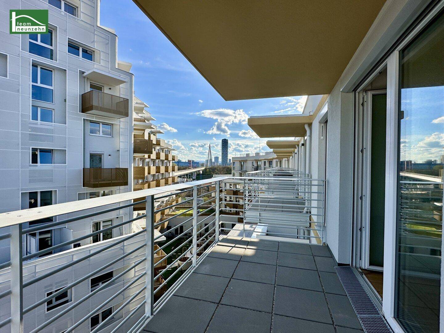 Geräumiger Balkon mit Fliesenboden und weitem Blick auf die Stadt und umliegende Gebäude.