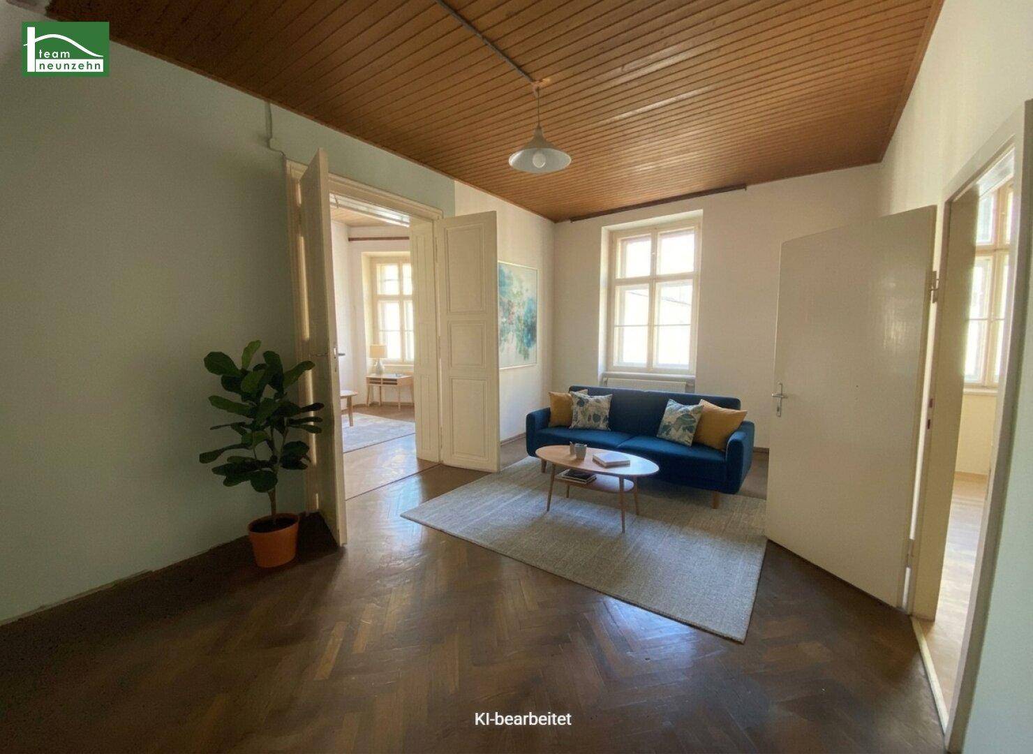 Gemütliches Wohnzimmer mit blauem Sofa, Holzboden und natürlichem Lichteinfall durch große Fenster.