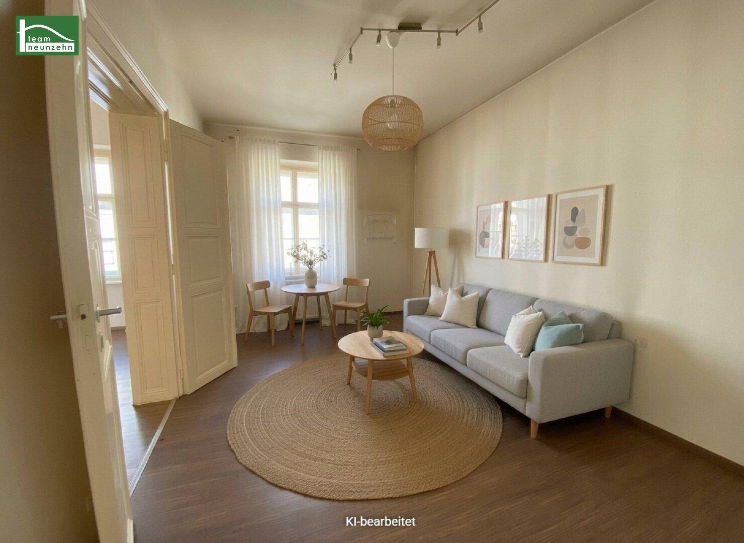 Helles Wohnzimmer mit Sofa, rundem Teppich und Zugang zu weiteren Räumen.