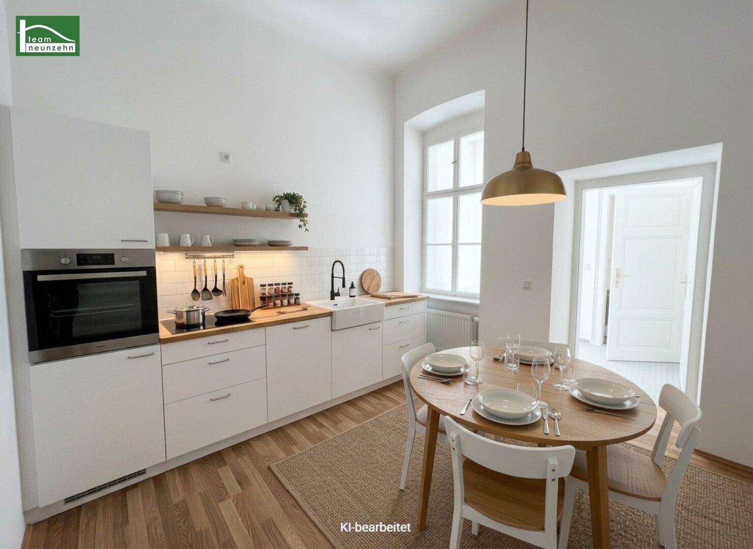 Moderne weiße Küche mit Holzarbeitsplatte, integriertem Backofen und Essbereich am Fenster.