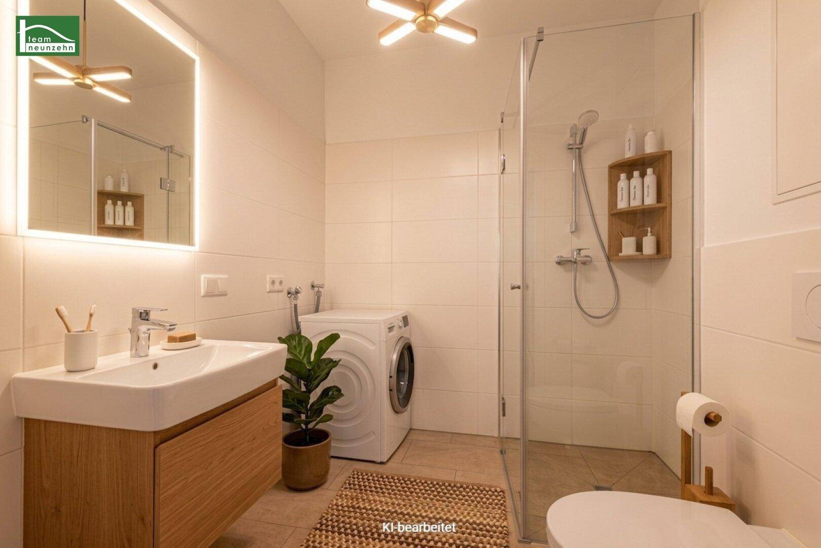 Modernes Badezimmer mit ebenerdiger Dusche, beleuchtetem Spiegel und integrierter Waschmaschine.